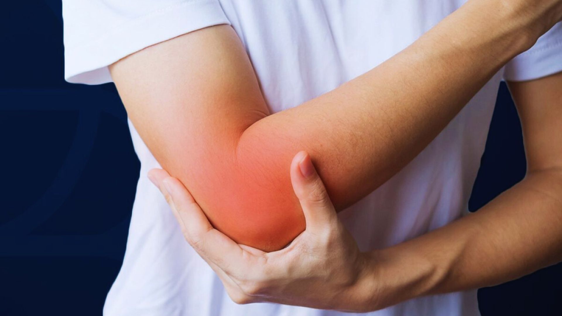 A person holds their inflamed, red elbow with a pained expression on their face, indicating discomfort or injury. They wear a white t-shirt against a dark background.