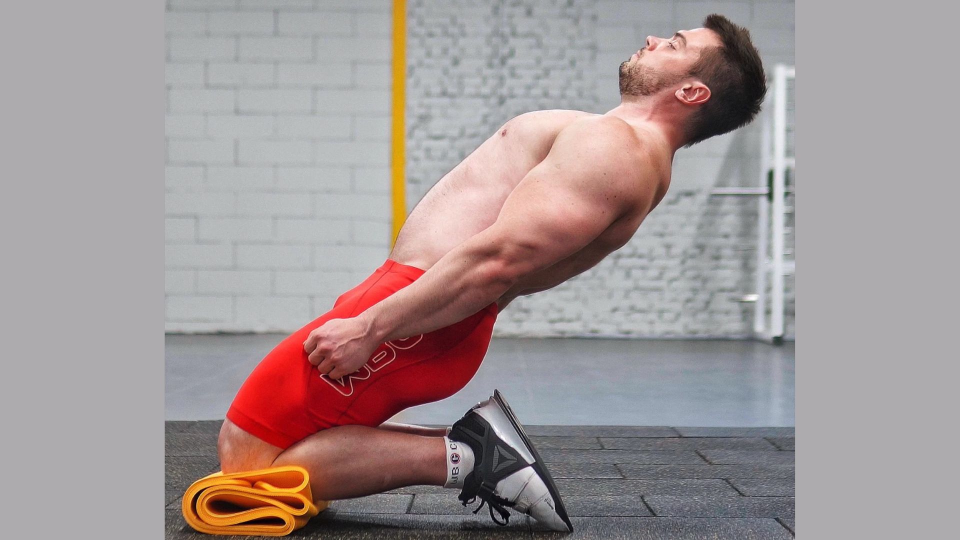 A man performs a squat while using a resistance band for added strength training.