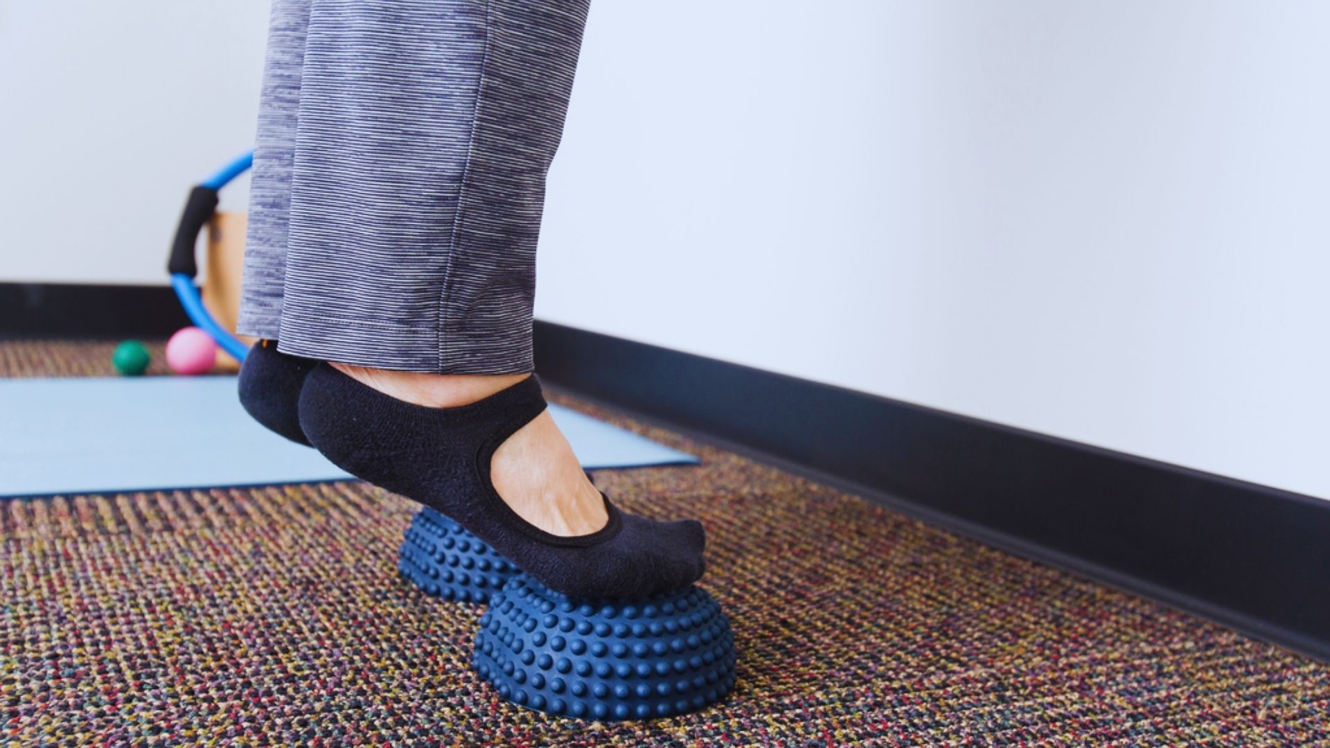 A person balances on a ball with their feet positioned on a mat, demonstrating stability and focus.