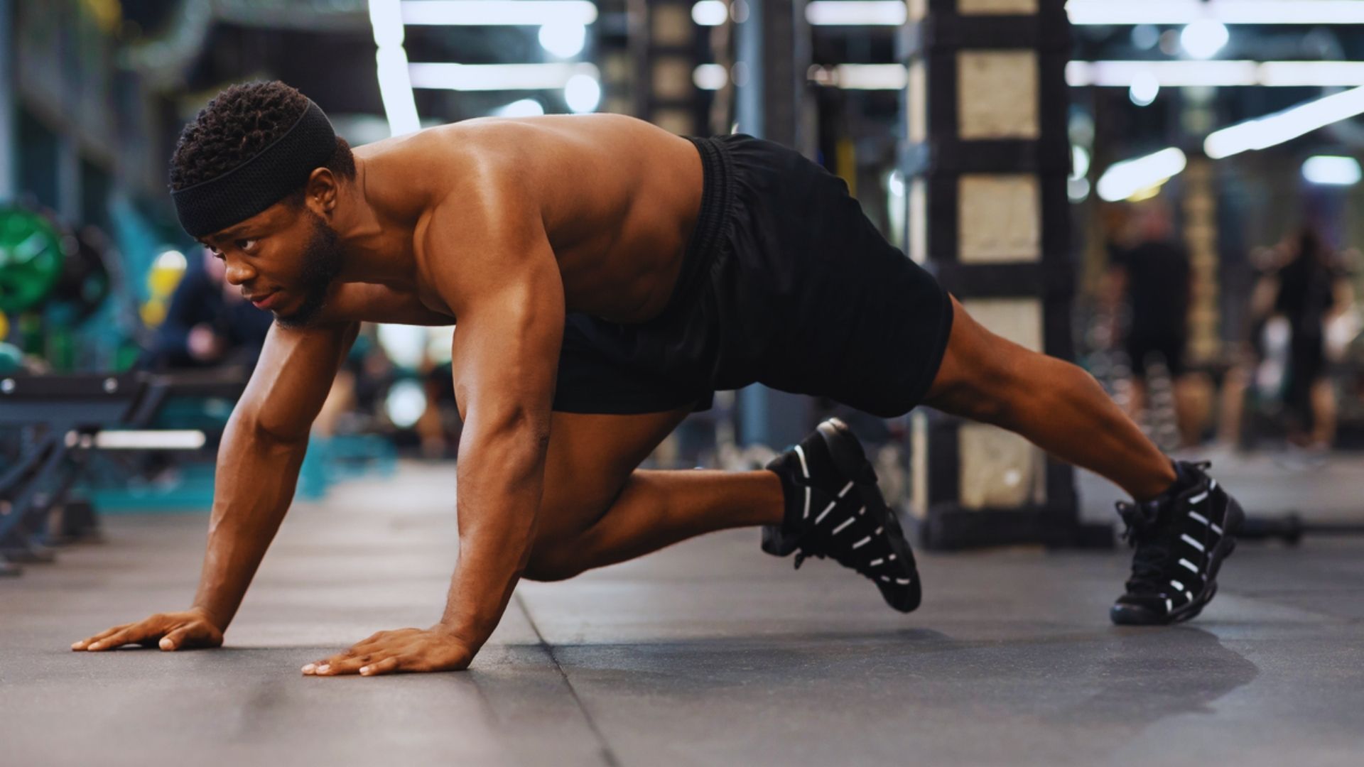 A man performing push-ups on a gym floor, focusing on his form and strength training.