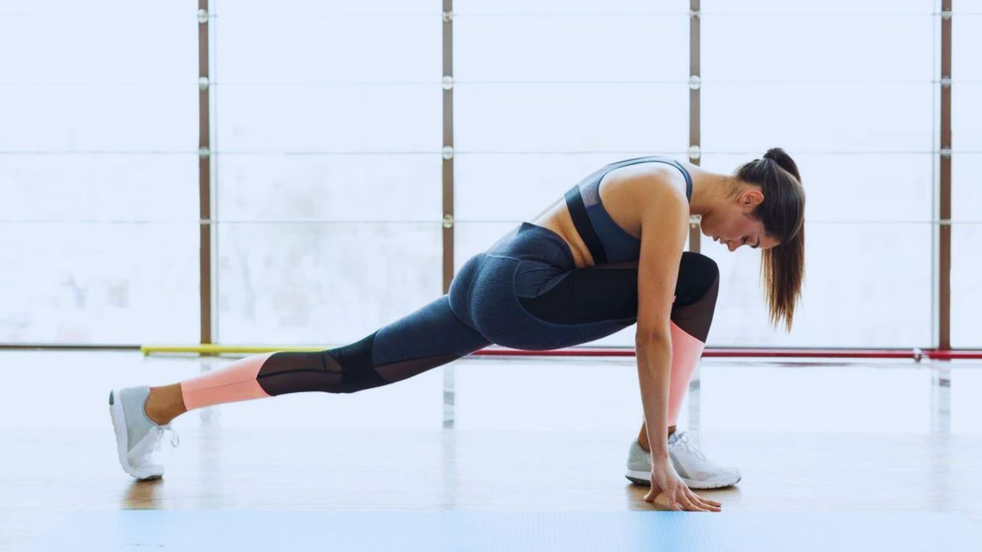 A woman in athletic wear performs a squat, demonstrating proper form and focus in a fitness setting.