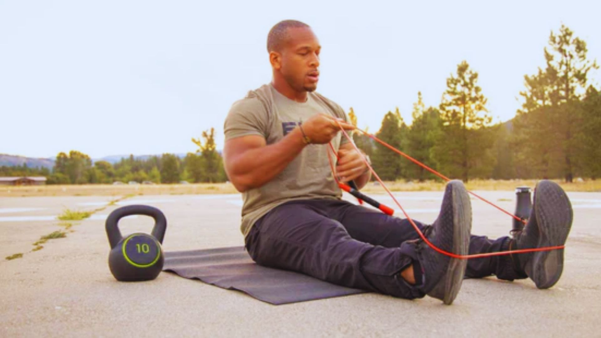 A man sits on the ground, holding a kettlebell, focused on his workout routine.