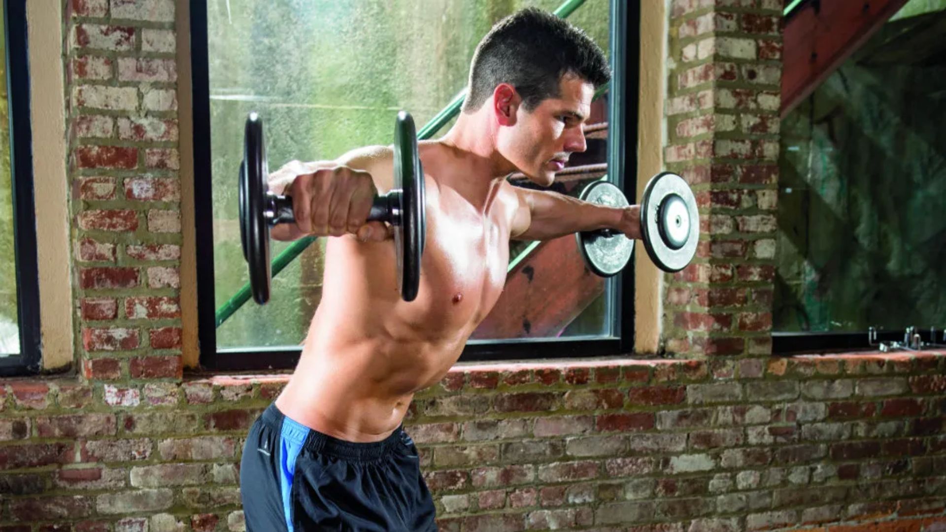 A man performs a workout, lifting a dumbbell with focus and determination.