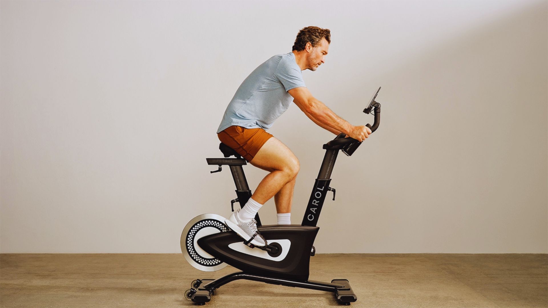 A man is exercising on a stationary bike in a fitness studio, focused on his workout.