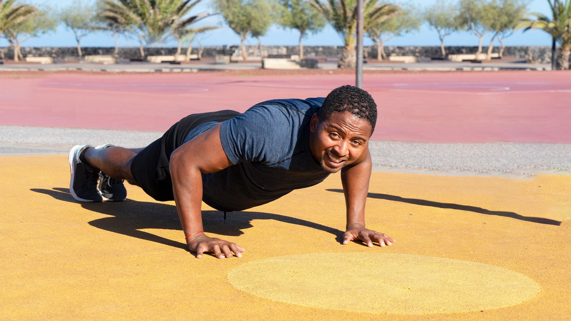 A man performing push-ups on a bright yellow surface, showcasing strength and fitness.