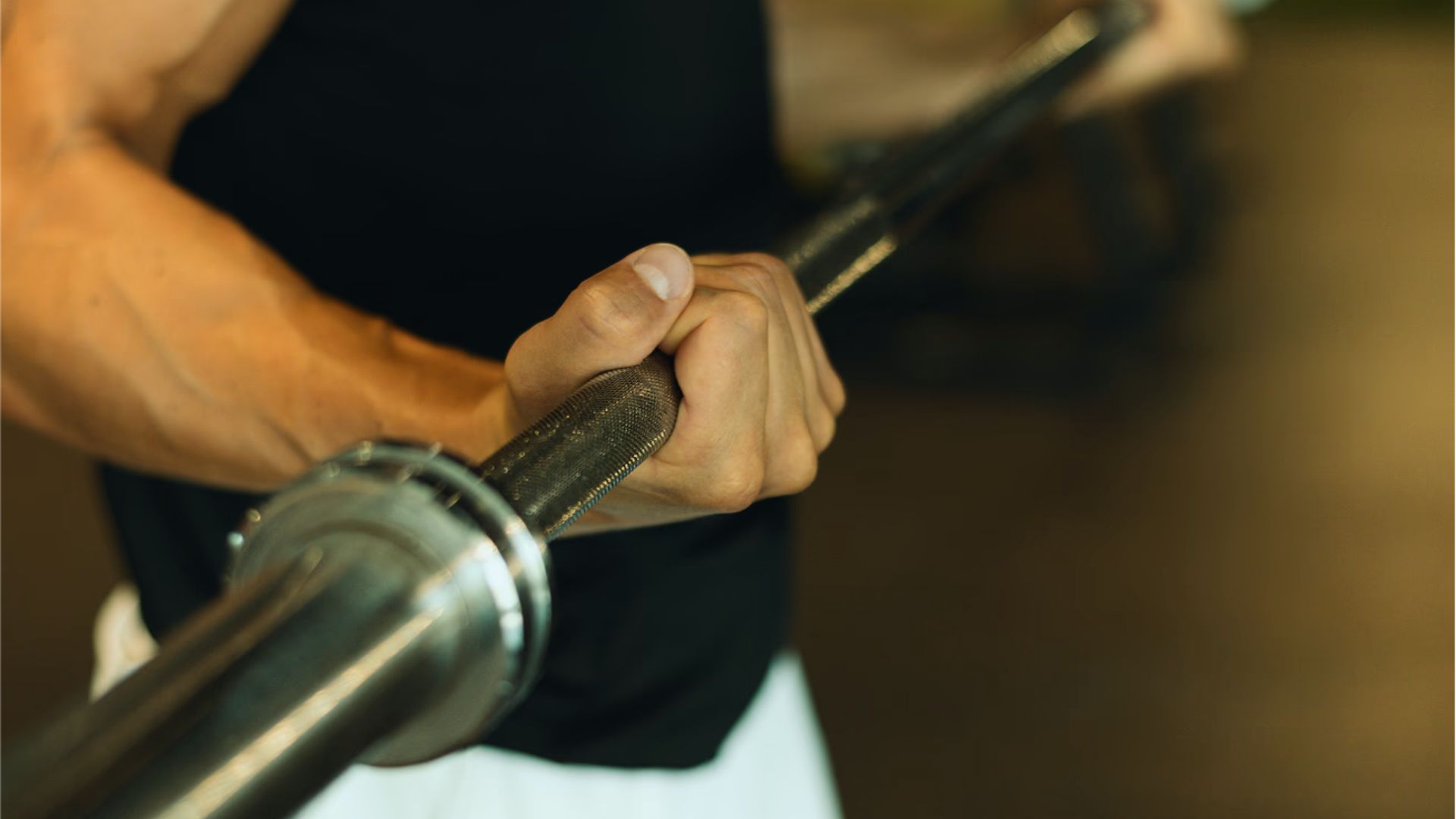A man lifts a barbell in a gym, focusing on his workout amidst exercise equipment.