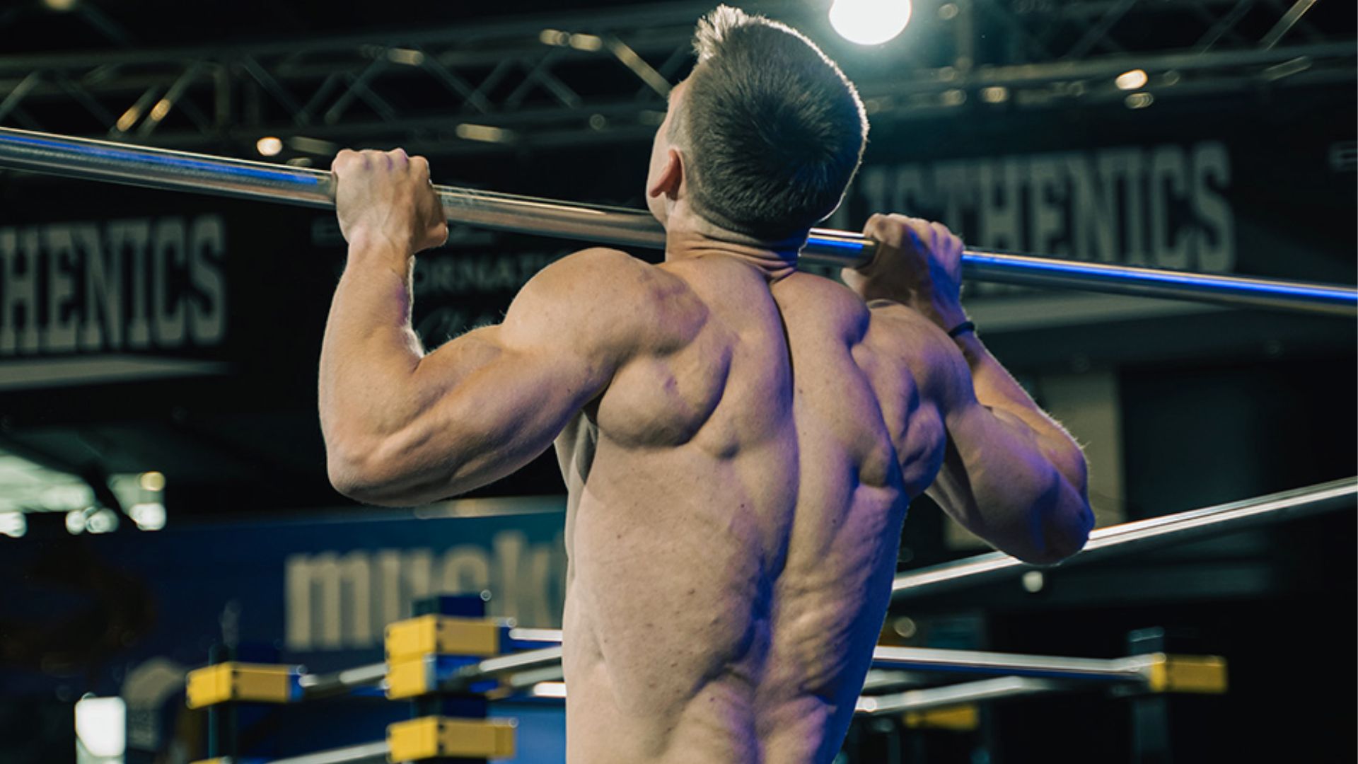 A man performs pull-ups on a horizontal bar, showcasing strength and fitness in an outdoor setting.