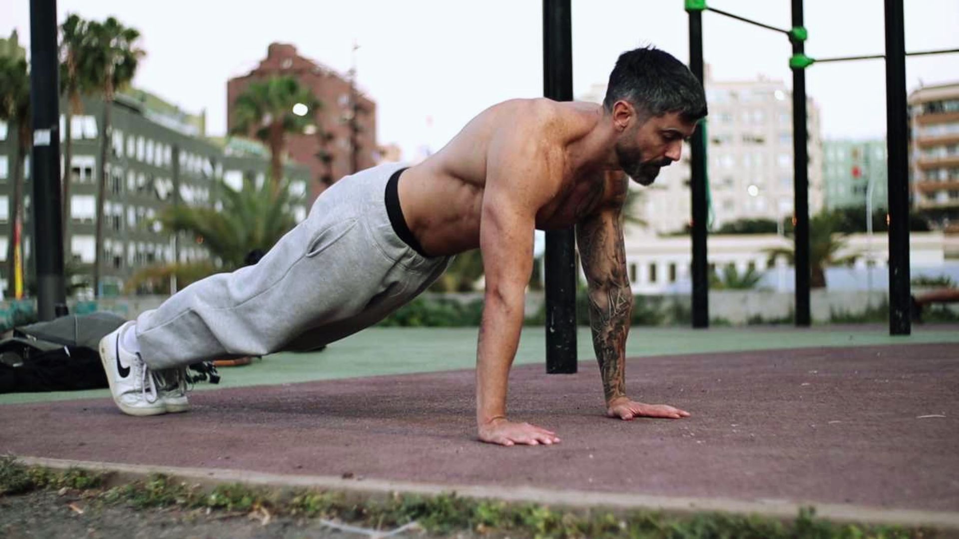 A man performing push-ups on a park bench, demonstrating fitness and strength in an outdoor setting.
