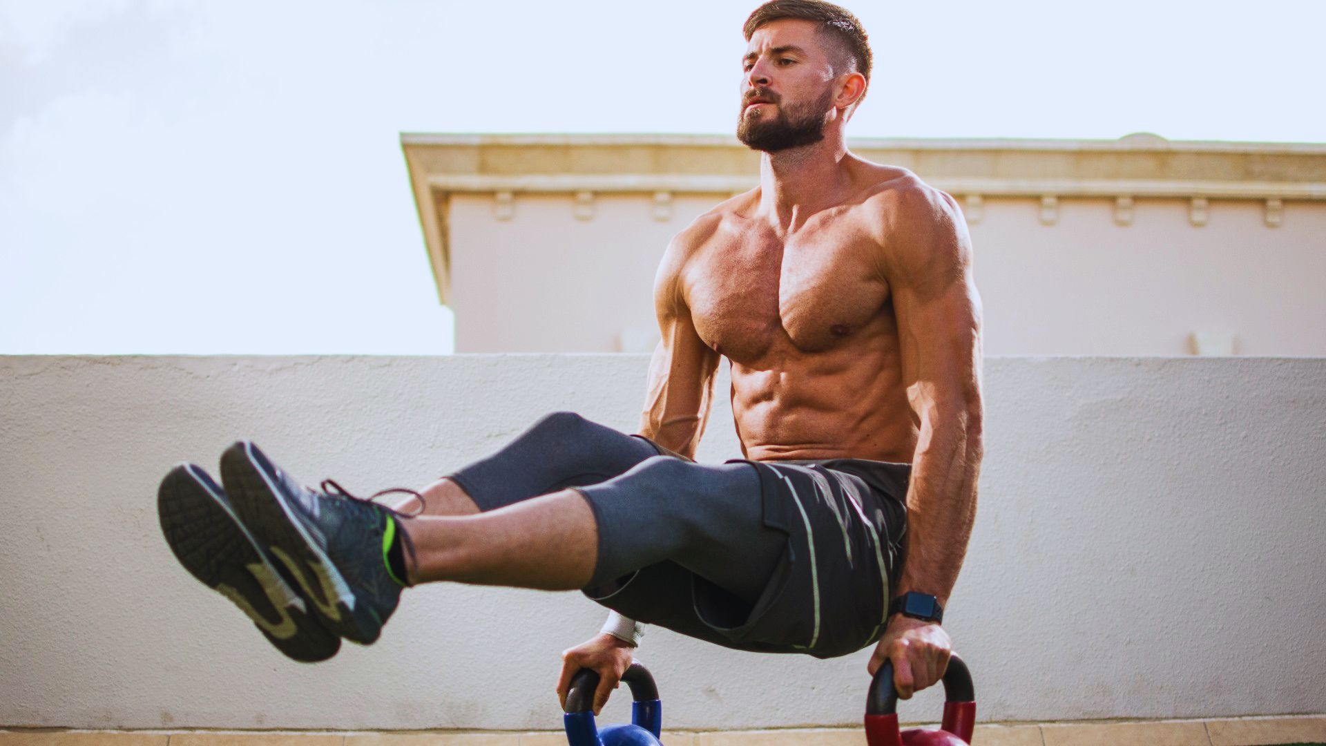 A man performing a push-up while gripping kettlebells for added resistance and strength training.