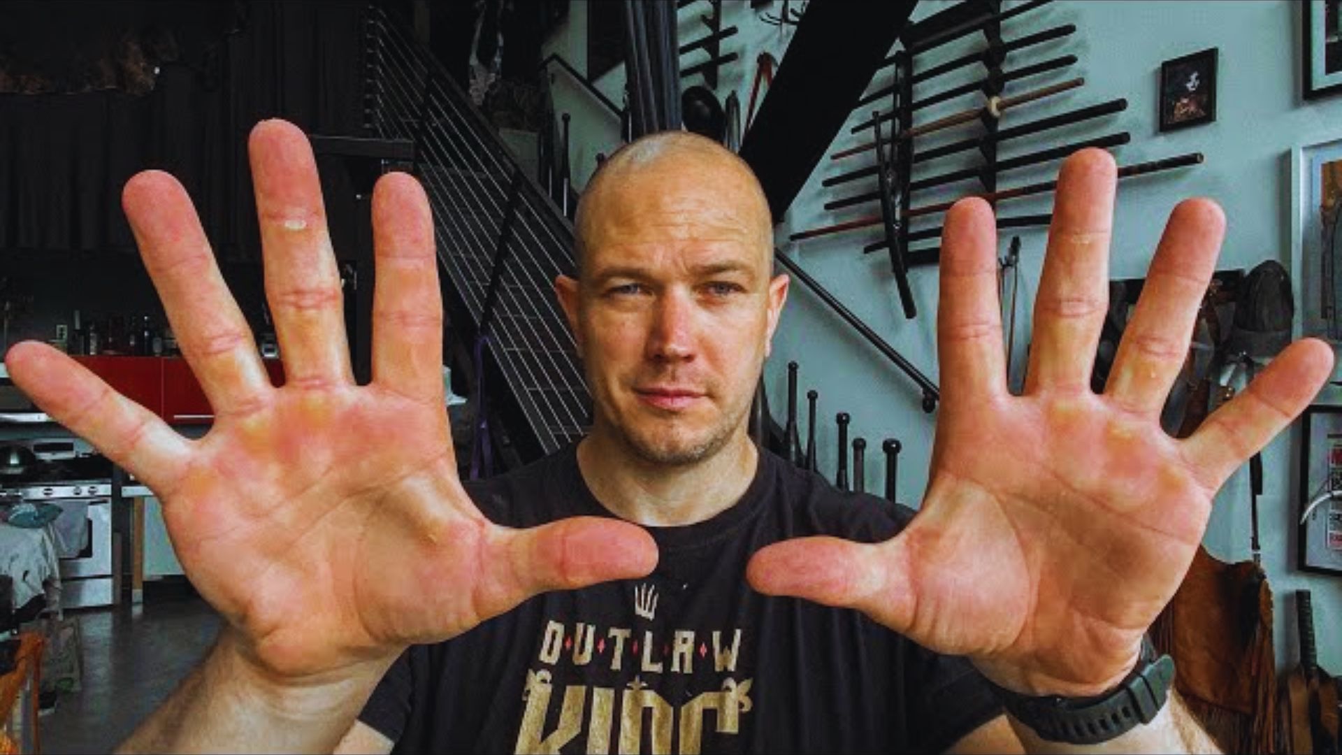 A man holds up his hands, displaying his fingers in a relaxed gesture.