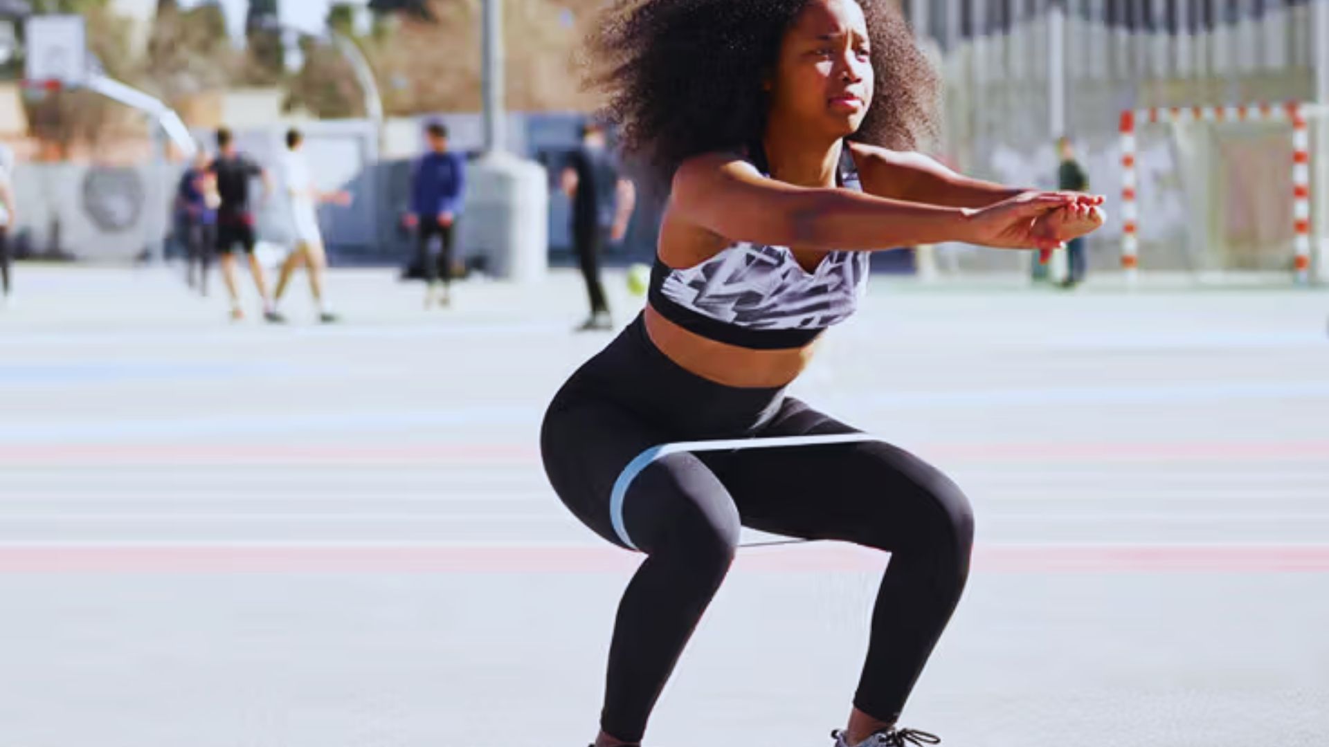 A woman performing squats on a basketball court, focusing on her fitness routine in a sports environment.