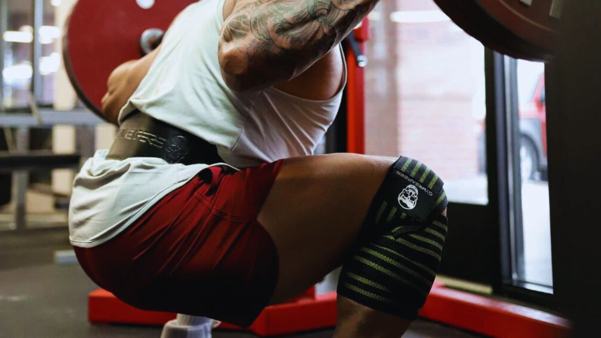 A man squats with a barbell on his shoulders in a gym, focusing on his form and strength training.