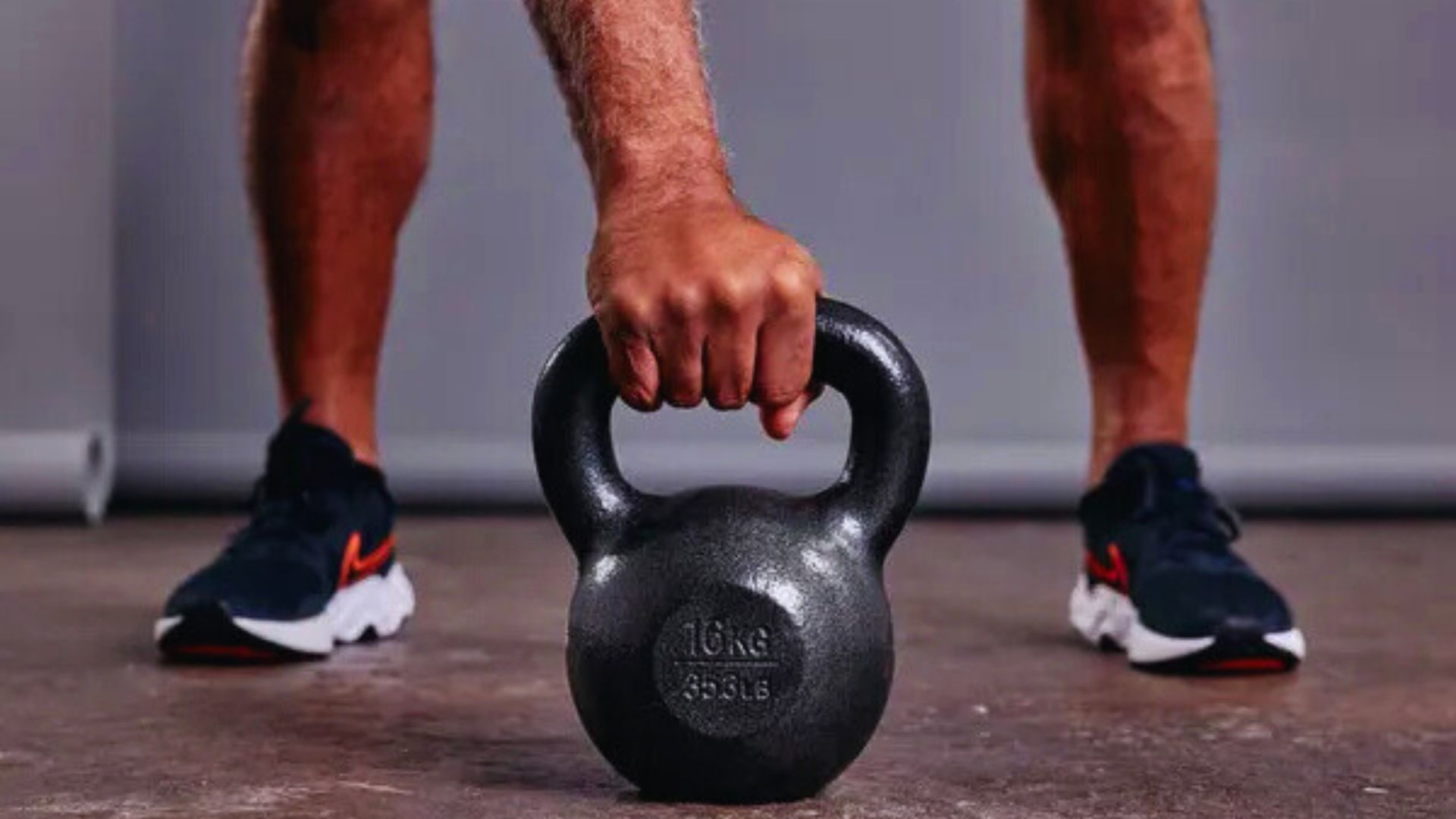 A man holds a kettlebell in one hand, demonstrating strength and fitness.