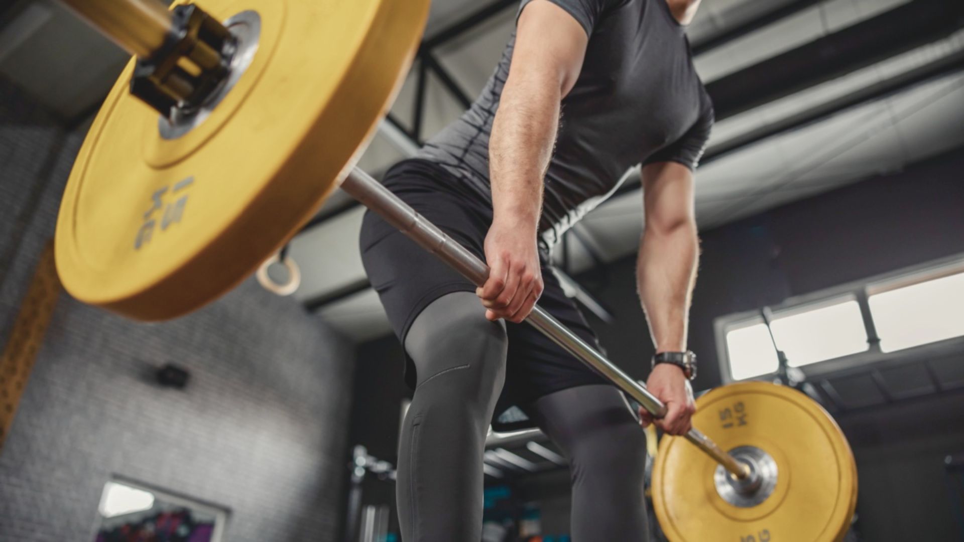 A man lifts a barbell in a gym, focusing on his strength training routine.