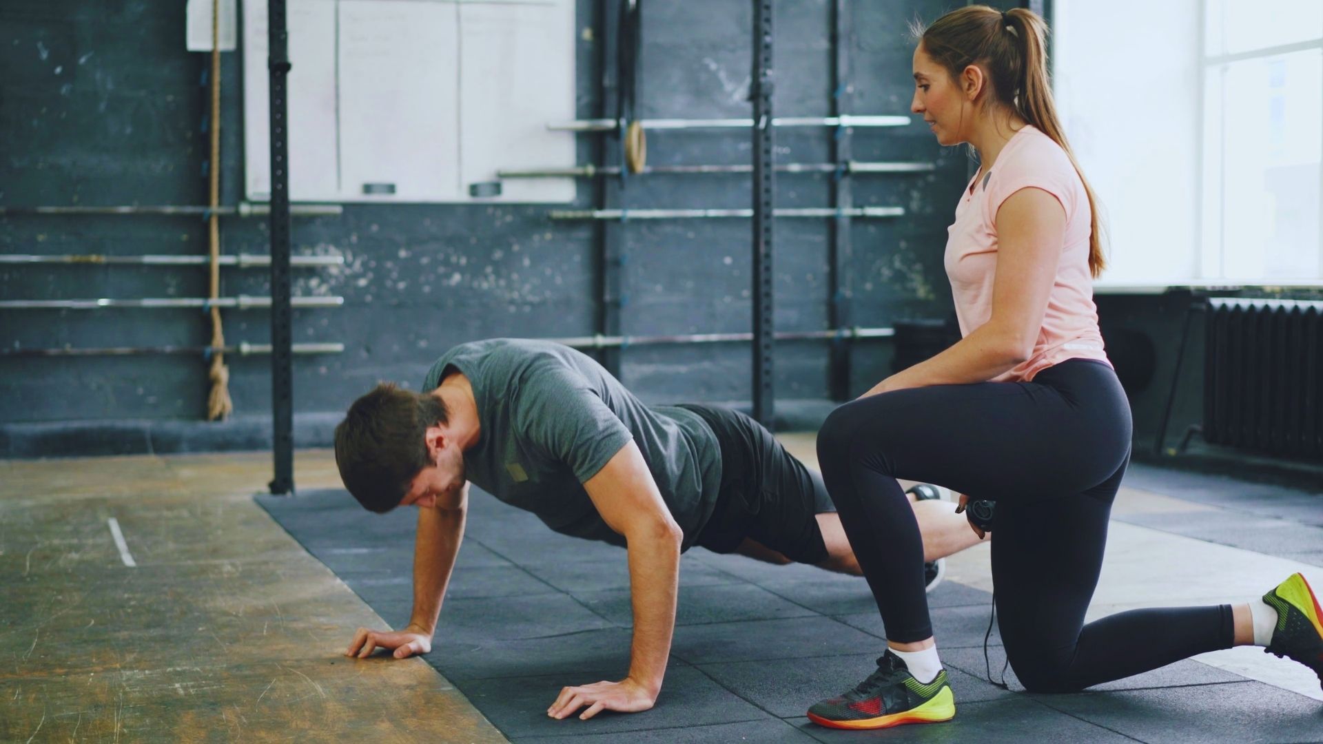 A man and woman performing push-ups side by side in a gym setting, focusing on their fitness routine.