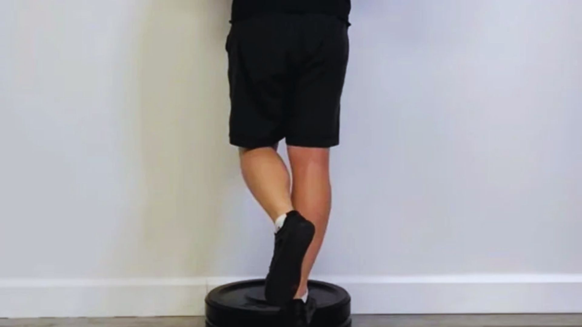 A person balances on a board, hands resting on a wall for support, demonstrating stability and focus.