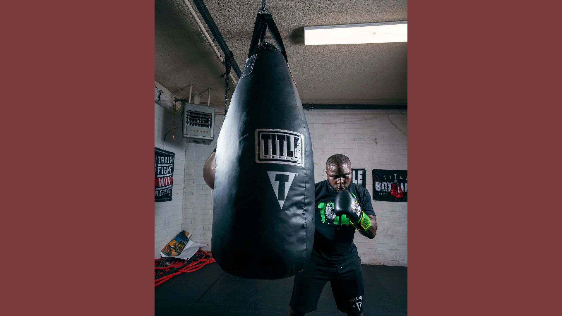 A man stands beside a punching bag, preparing for a workout in a gym setting.