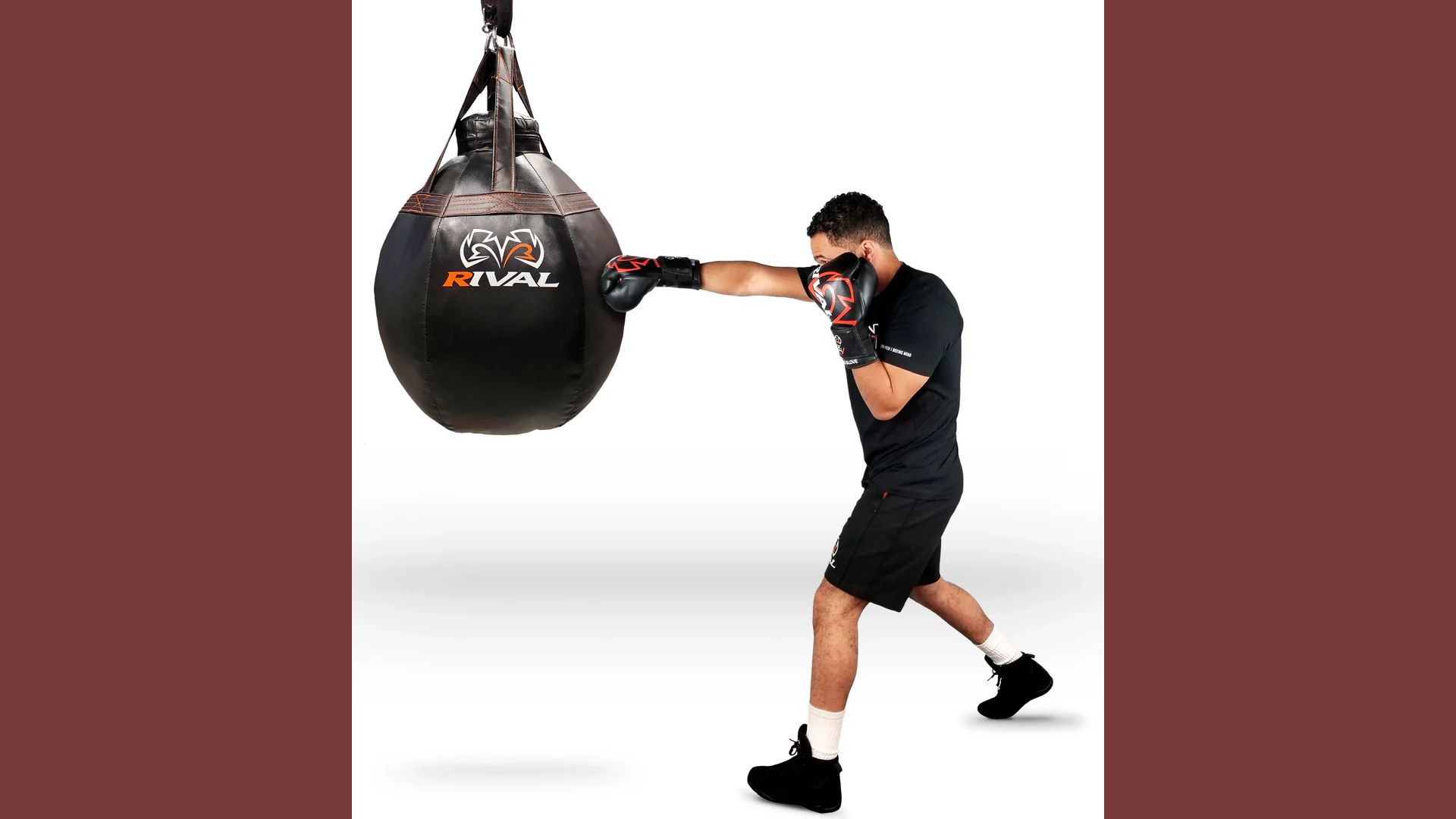 A man strikes a punching bag with a black bag, demonstrating his boxing technique in a gym setting.