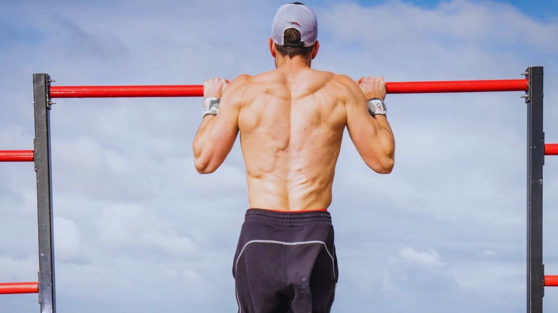 A man performs pull-ups on a bar, showcasing strength and fitness in a gym setting.