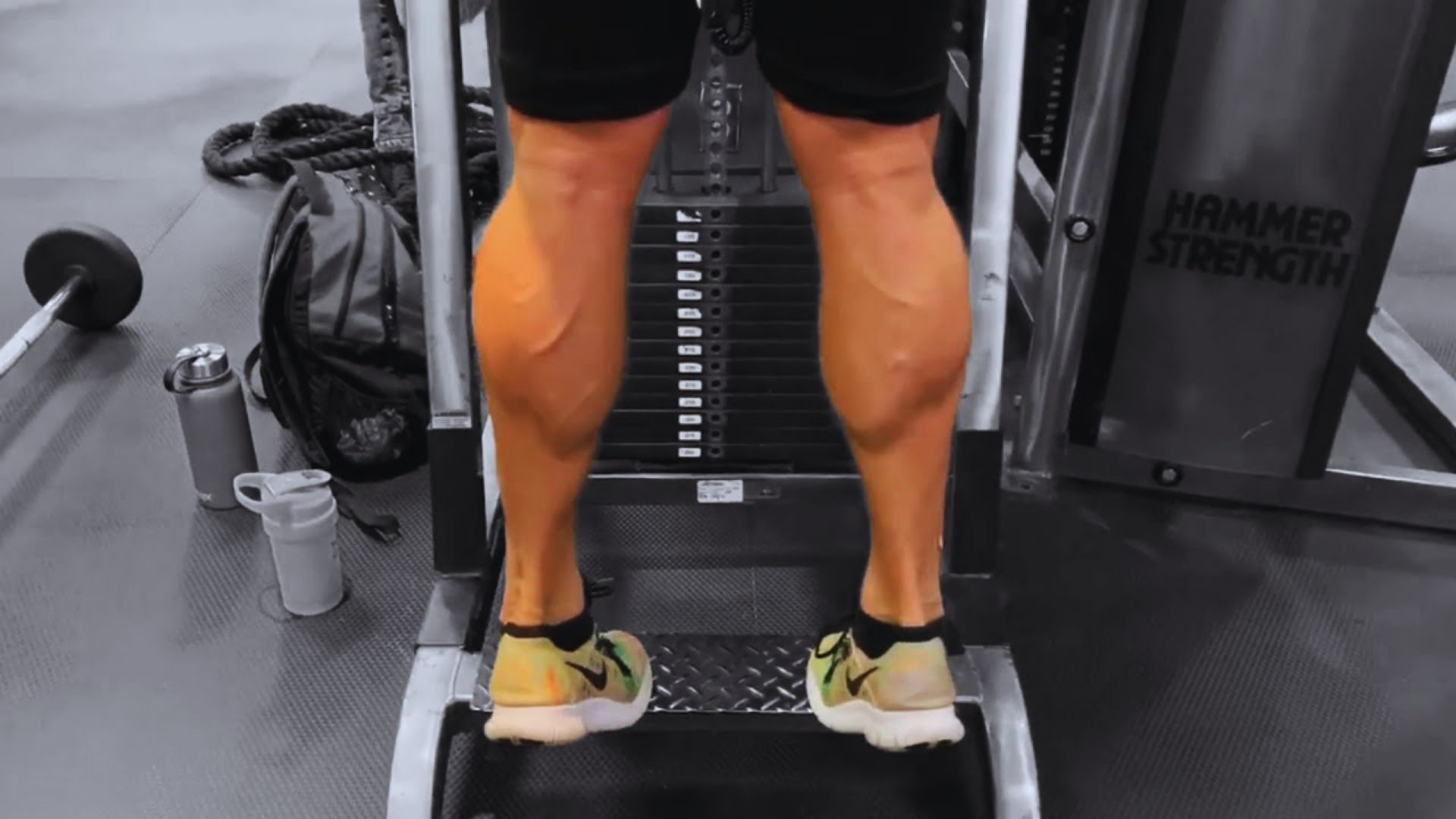 A person stands on a gym machine, preparing to exercise in a well-equipped fitness environment.
