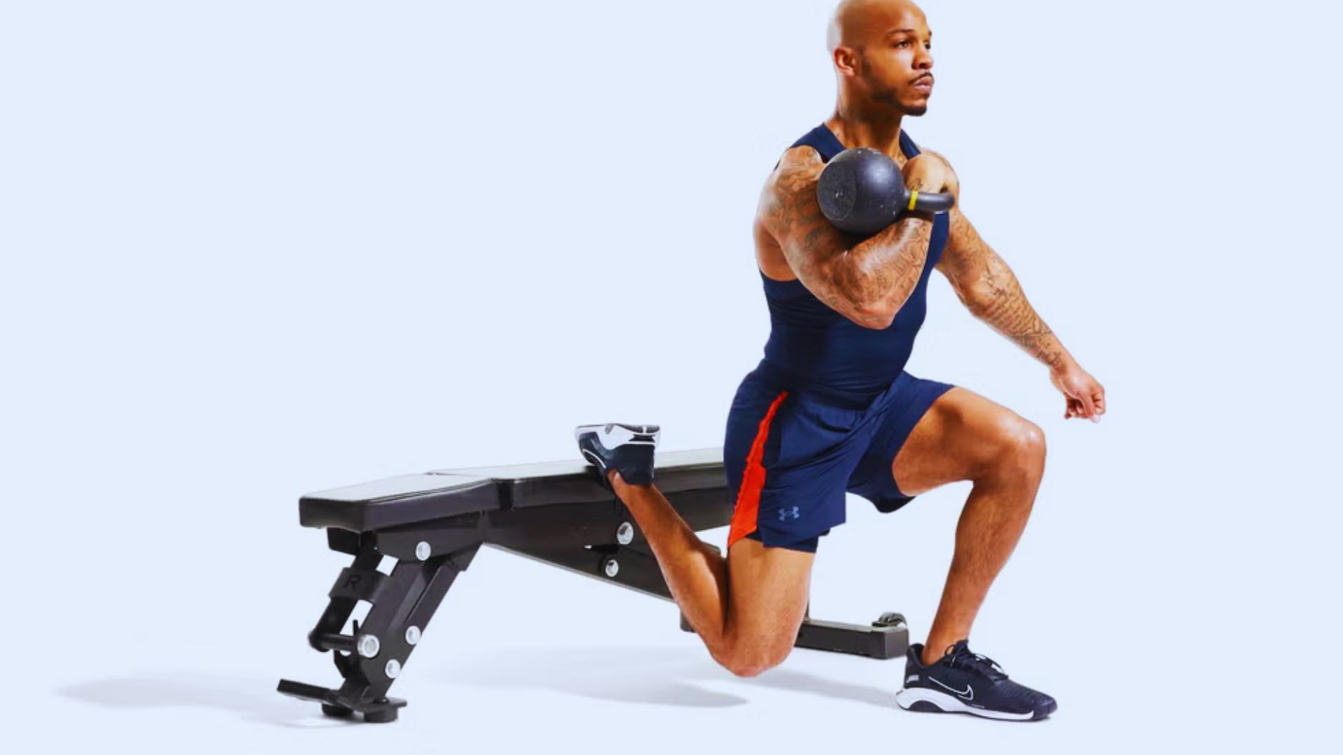 A man squats on a bench while holding a dumbbell in his right hand, focusing on his workout.