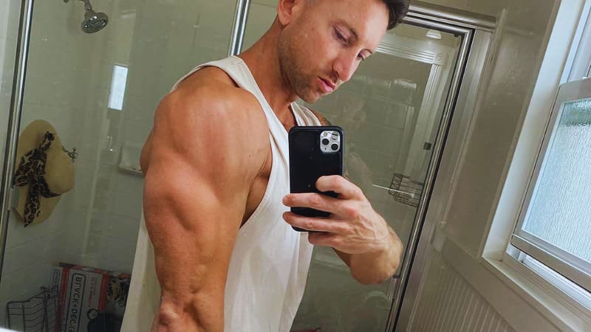 A man smiling while taking a selfie in the mirror, capturing his reflection and the surrounding room.