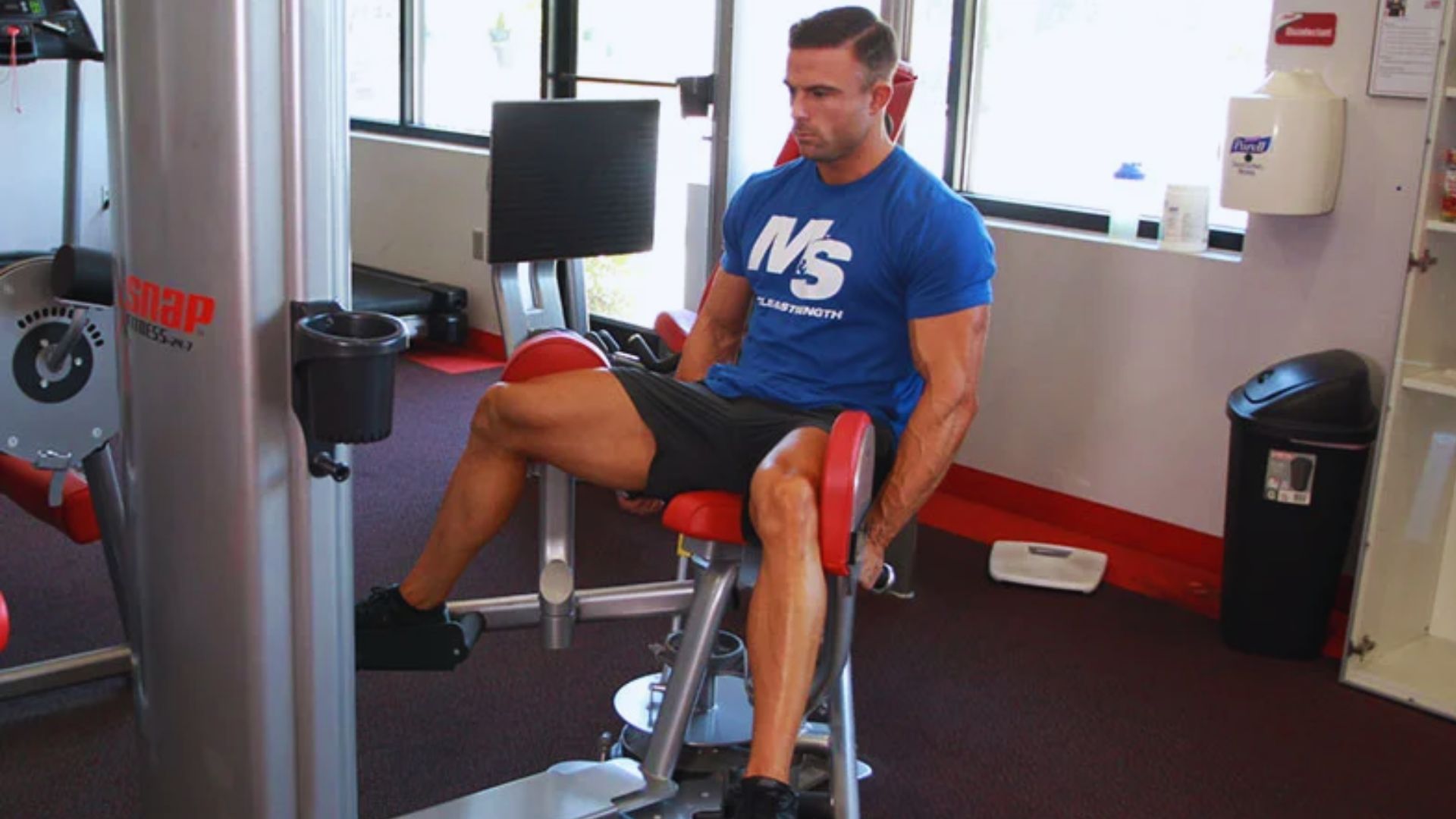 A man sits on a gym machine, focused on his workout in a well-equipped fitness center.