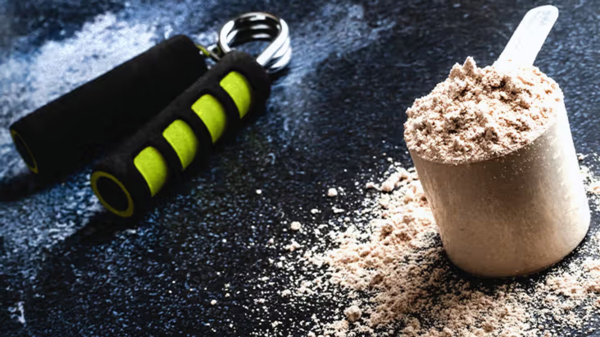 A scoop of protein powder beside a pair of dumbbells on a flat surface, suggesting fitness and nutrition.