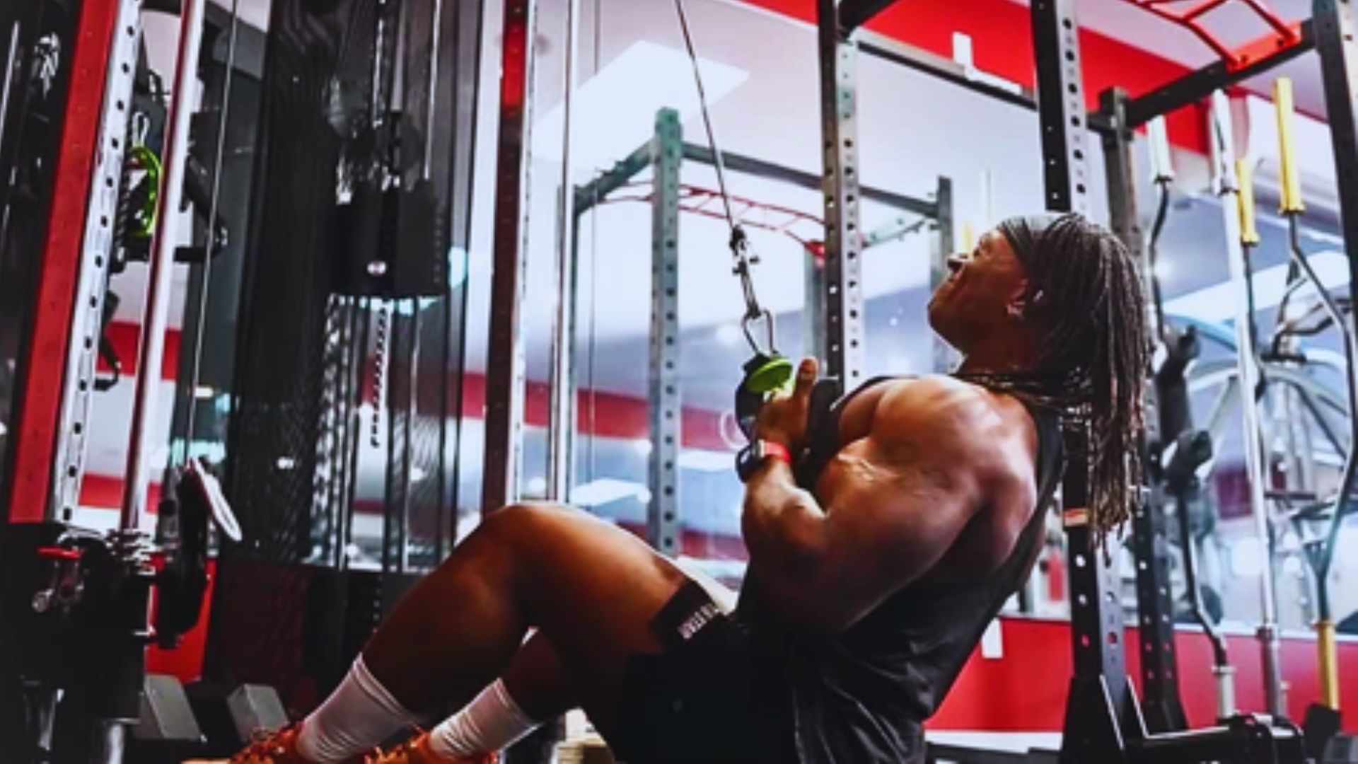 A person working out in a gym, performing a cable pull exercise. They are wearing athletic gear, showcasing strength and focus amidst gym equipment.