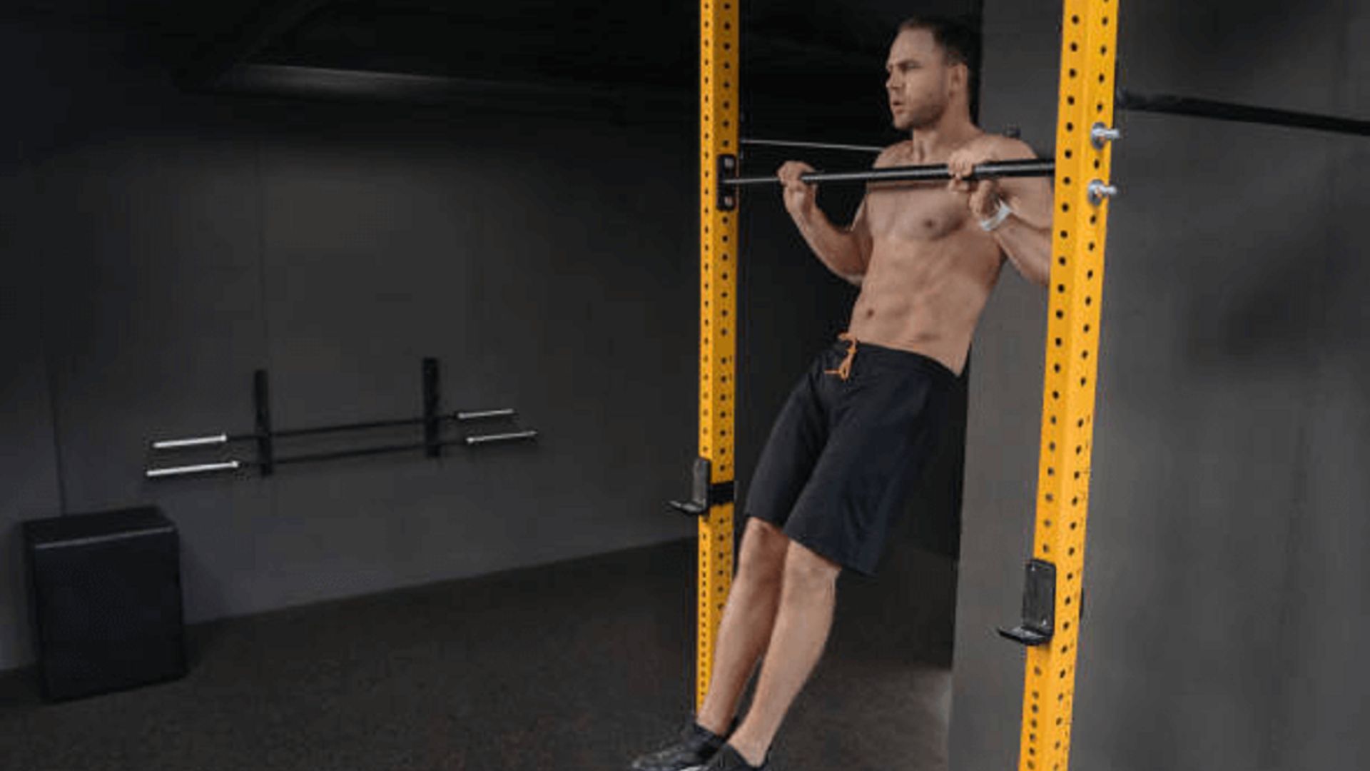 A man performs pull-ups on a bar, showcasing strength and fitness in a gym setting.