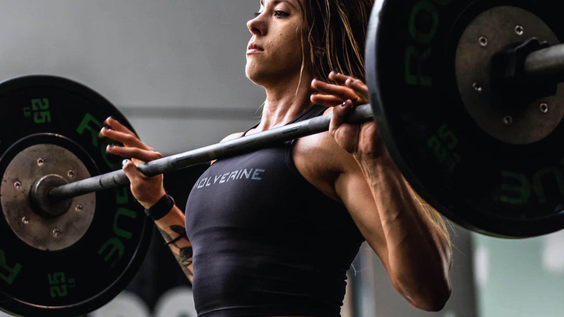 A woman lifts a barbell in a gym, demonstrating strength and focus during her workout session.