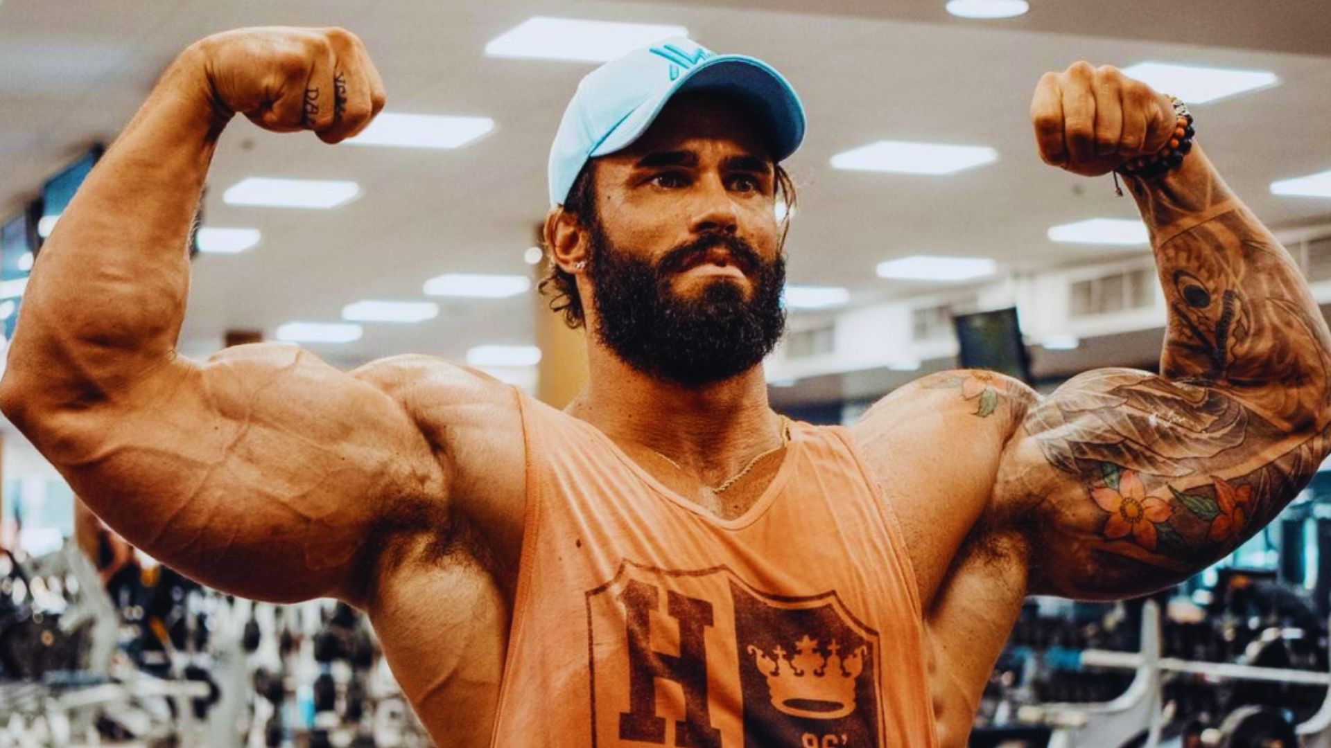 A bearded man with tattoos exercises in a gym, showcasing strength and determination.