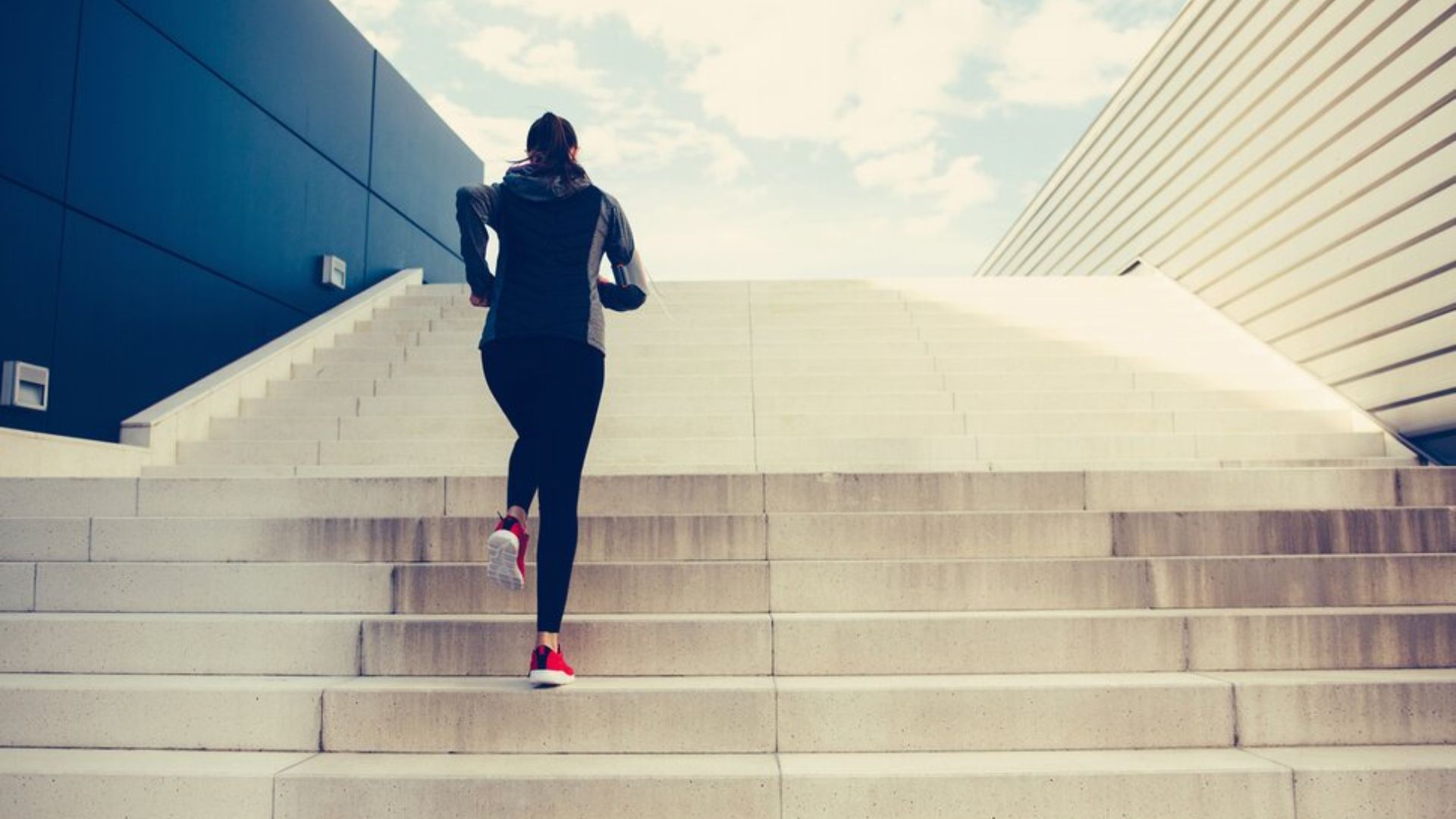 A woman is energetically running up a flight of stairs, showcasing determination and physical fitness.