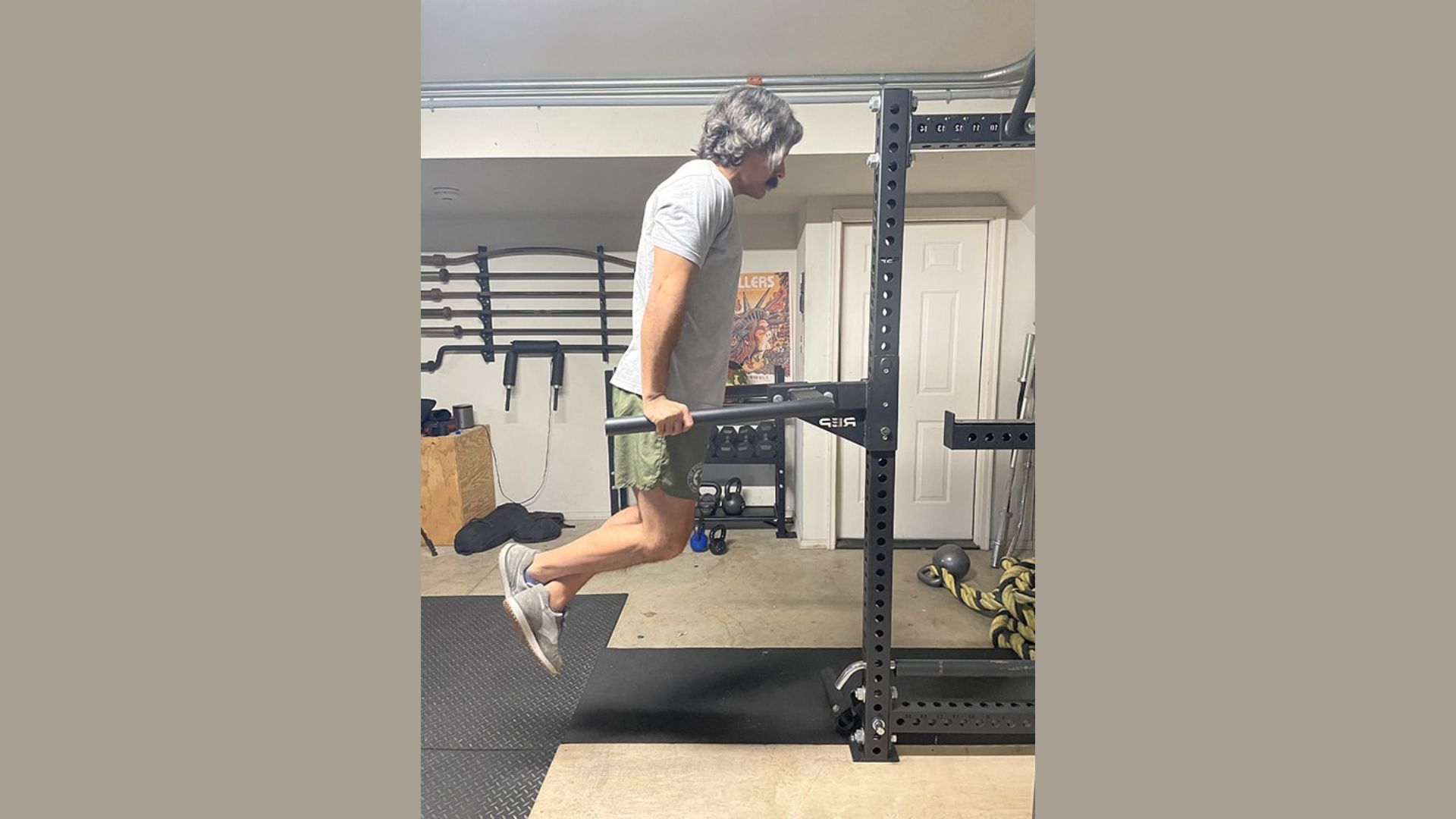A man performs a pull-up on a bar in a gym, showcasing strength and focus during his workout.