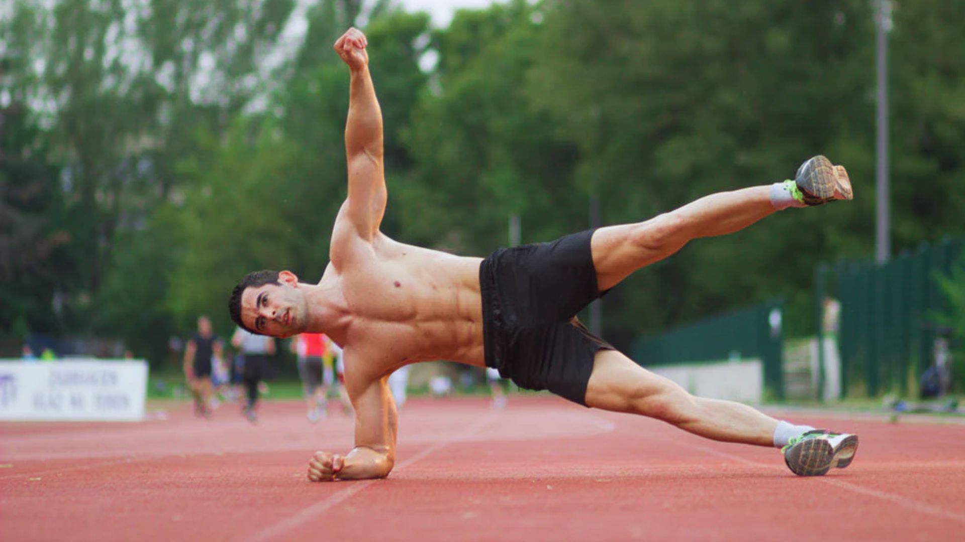 A man performing a split on a running track, showcasing flexibility and athleticism in a dynamic pose.