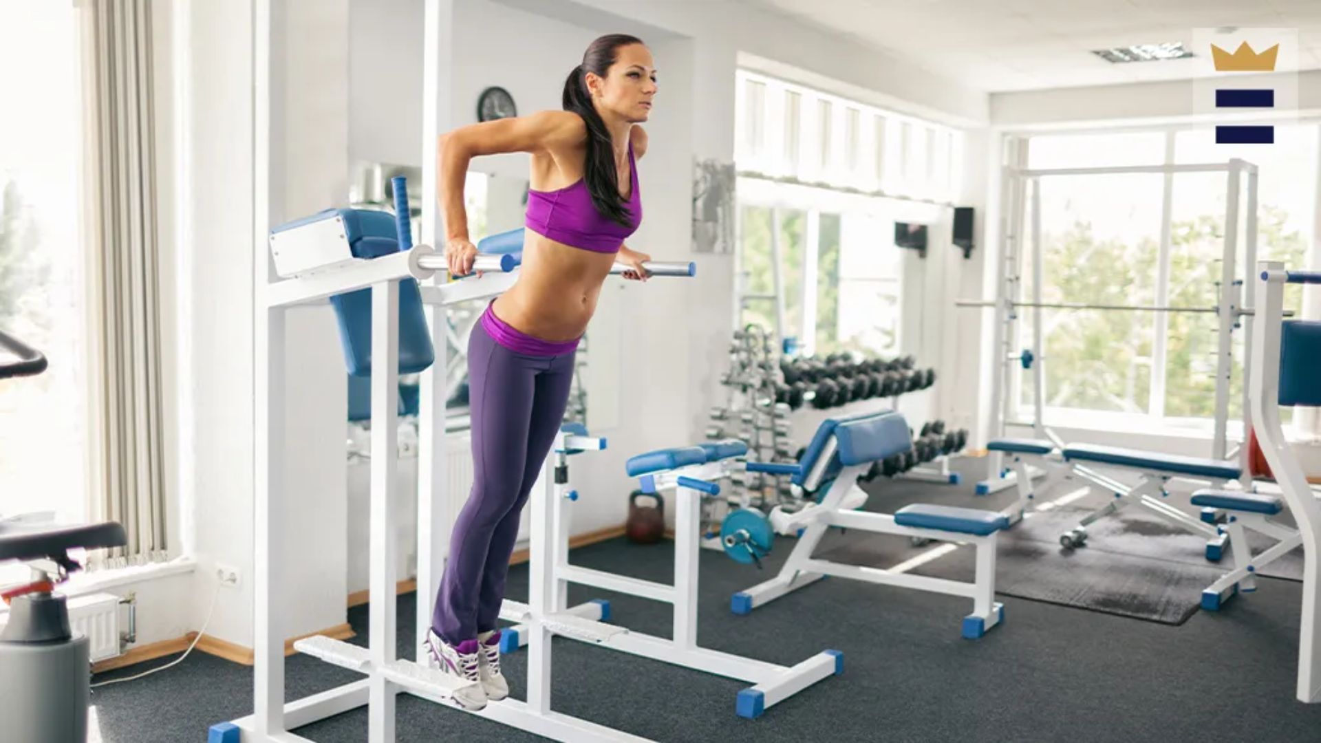 A woman performs a pull-up on a gym machine, showcasing strength and focus in her workout routine.