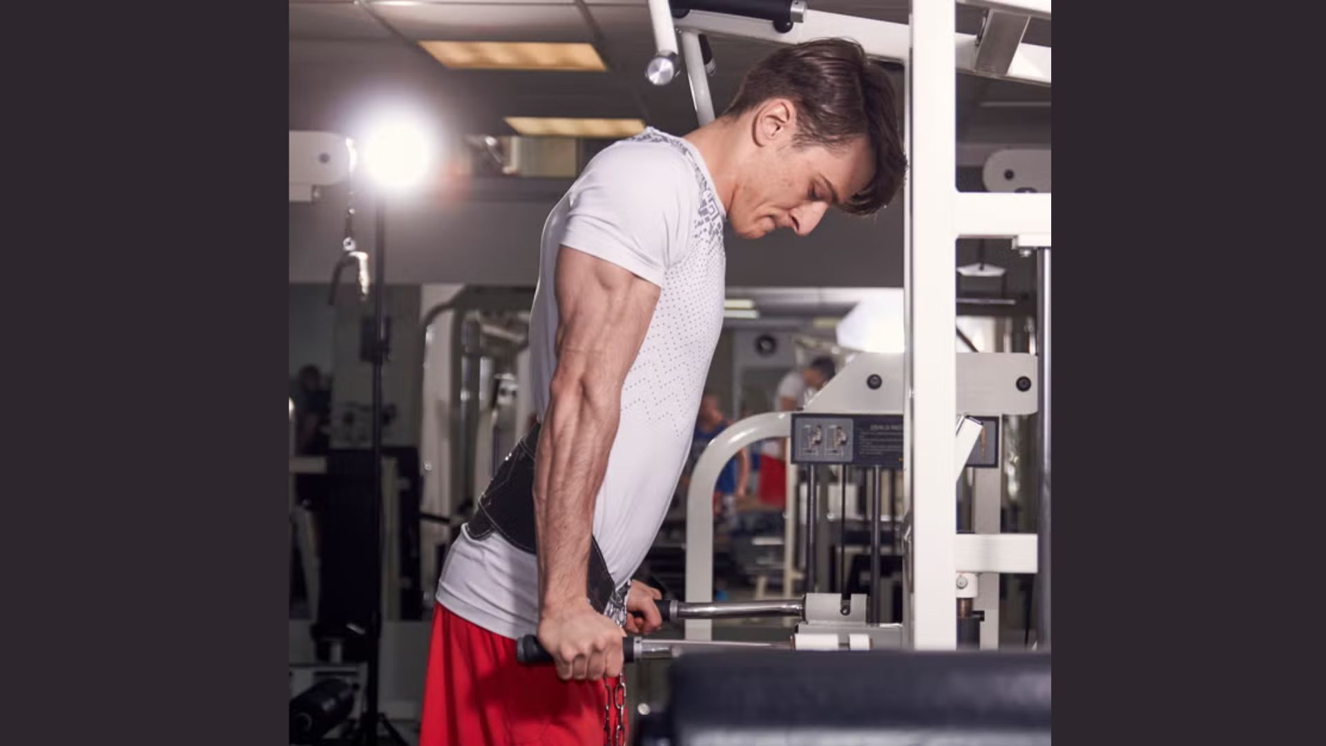 A man performs a bicep curl with a dumbbell in a gym, focusing on strength training.