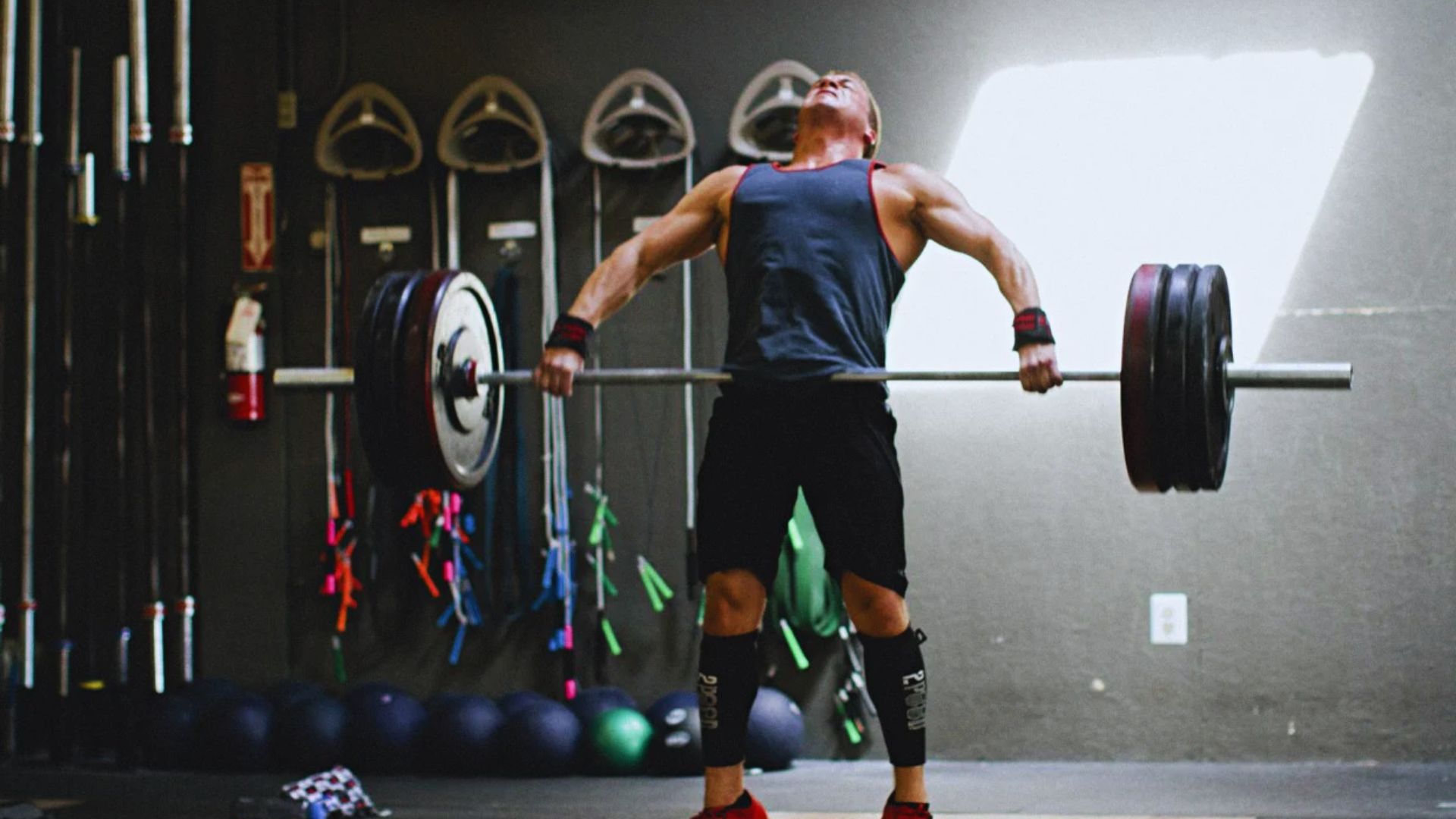 A man lifts a barbell in a gym, focusing on his strength training routine.