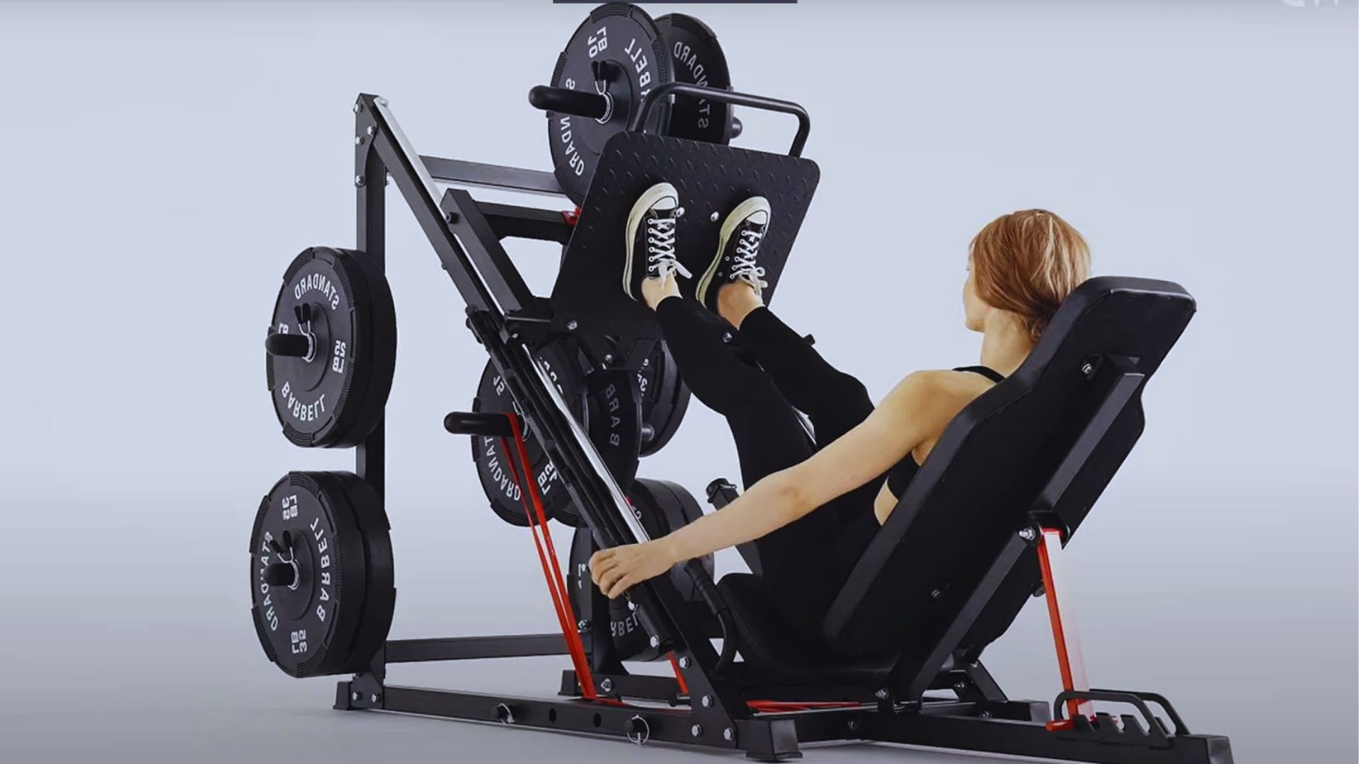 A person in athletic wear uses a leg press machine, pushing against a weighted platform. The scene conveys strength and focus in a gym setting.