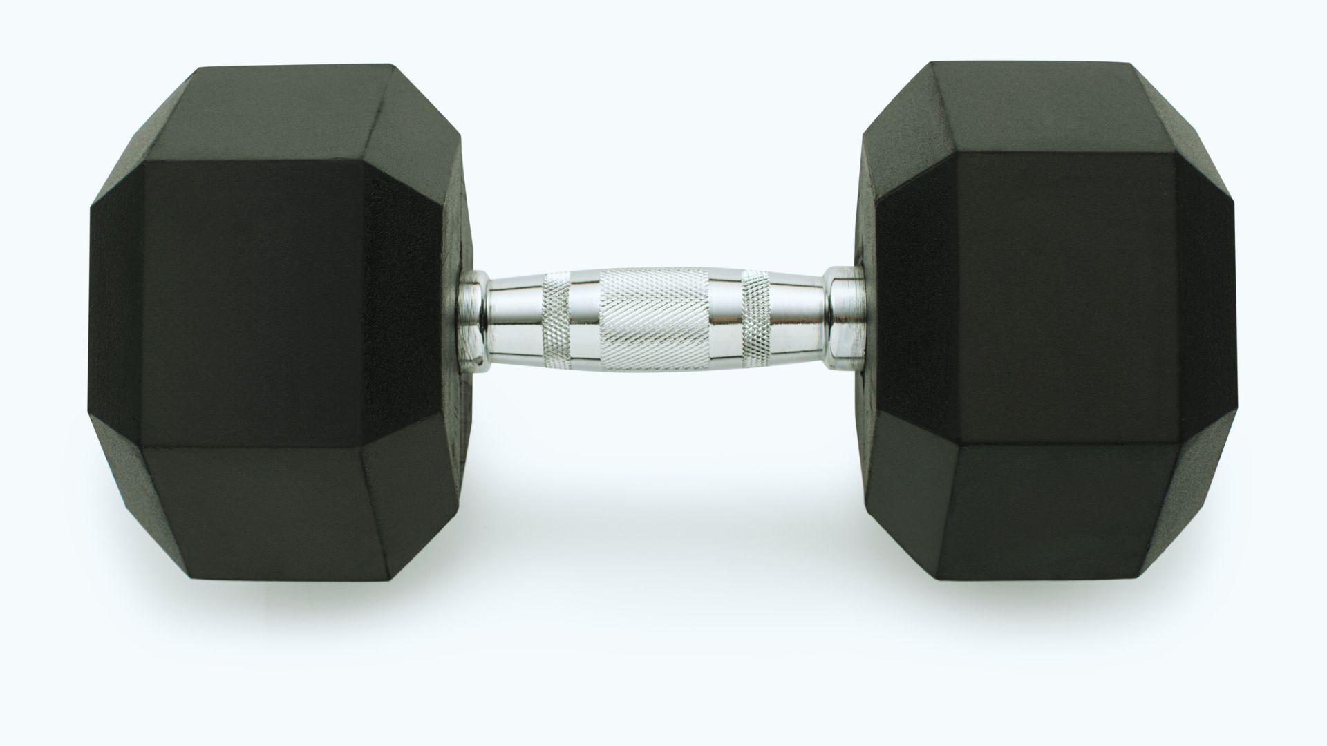 A black hexagonal dumbbell with a textured silver handle, centered on a plain white background, conveying a sense of fitness and strength.