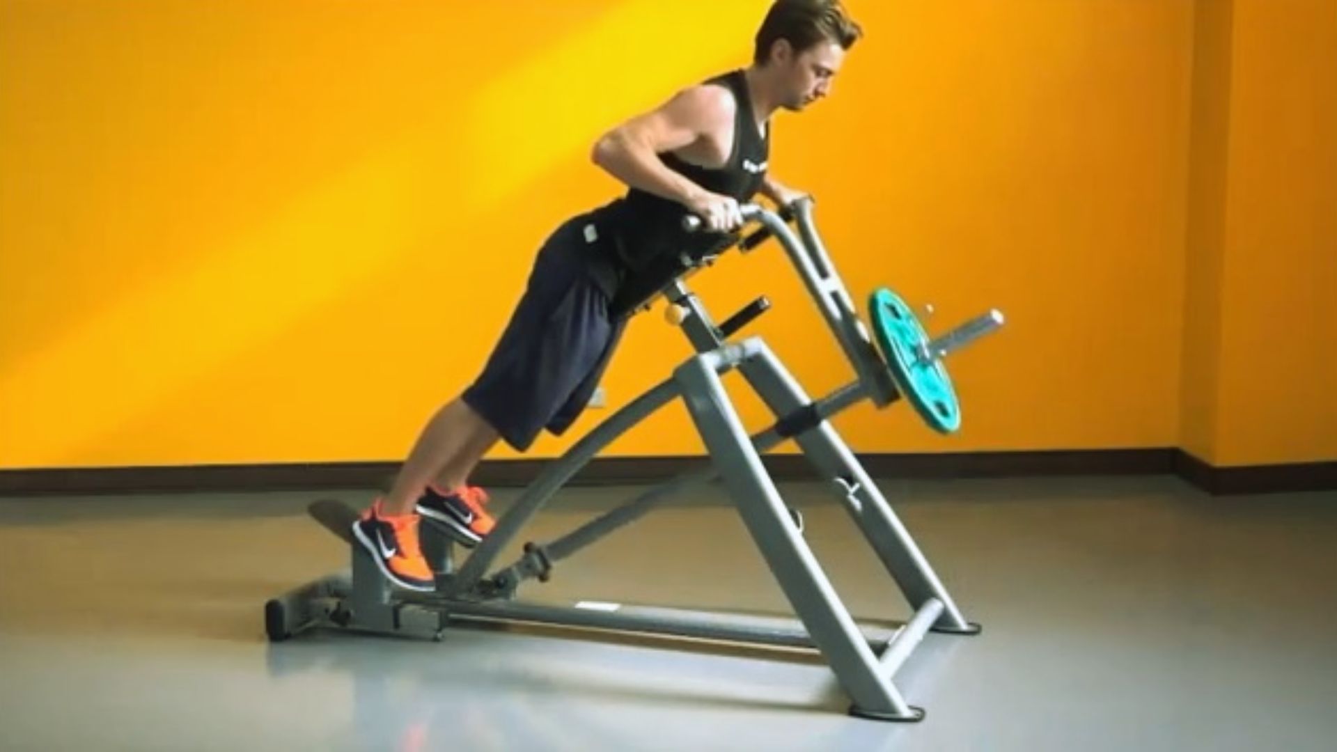 A person in athletic wear uses a back-extension exercise machine in a gym, against a bright yellow wall, conveying focus and strength.
