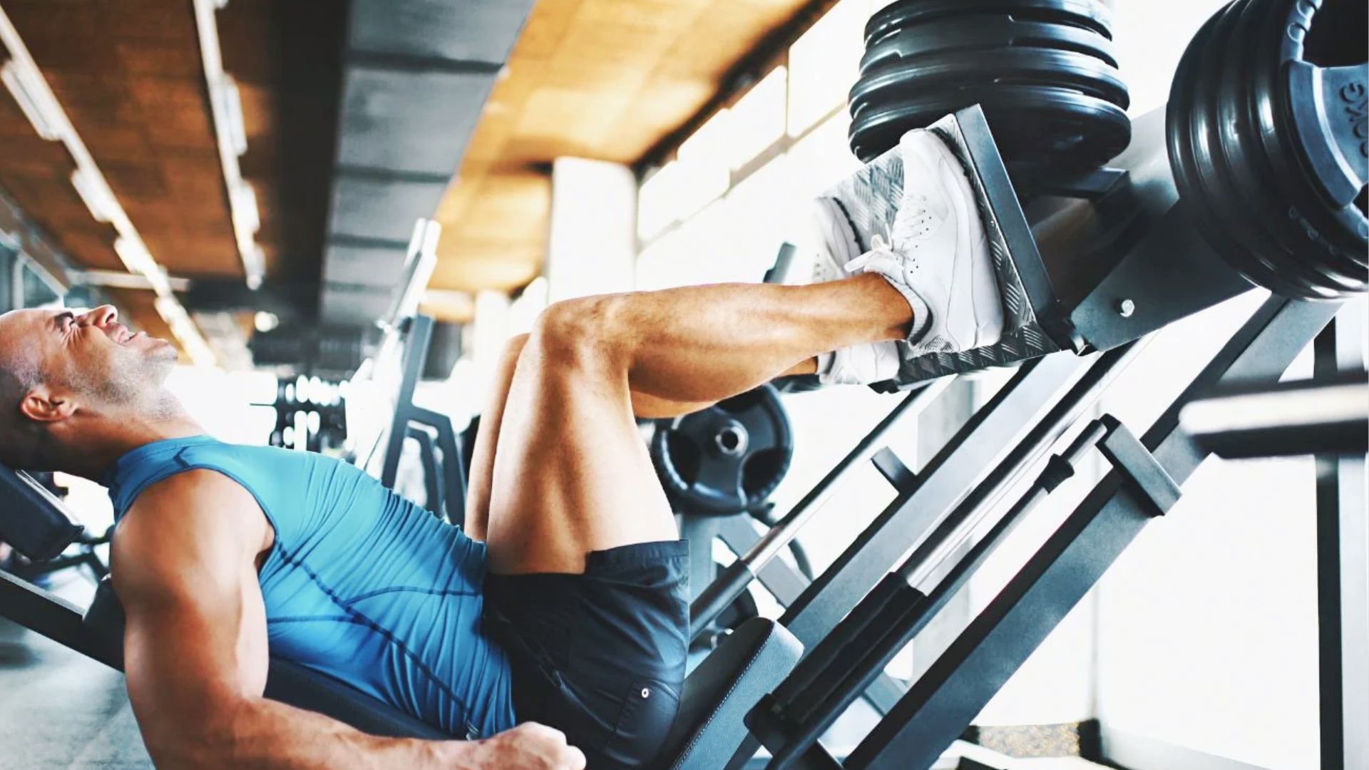 A person performing a leg press exercise in the gym, showing effort while pushing weight on a leg press machine.