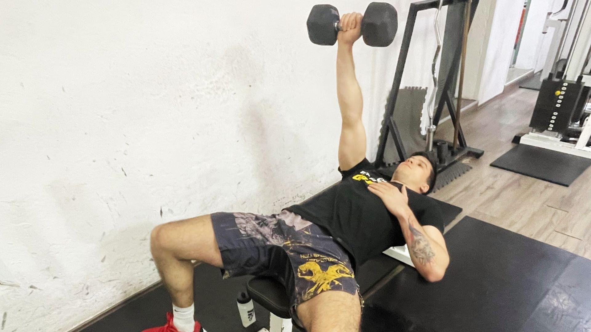 Person performing single-arm dumbbell press on a bench focusing on unilateral chest strength and muscle balance