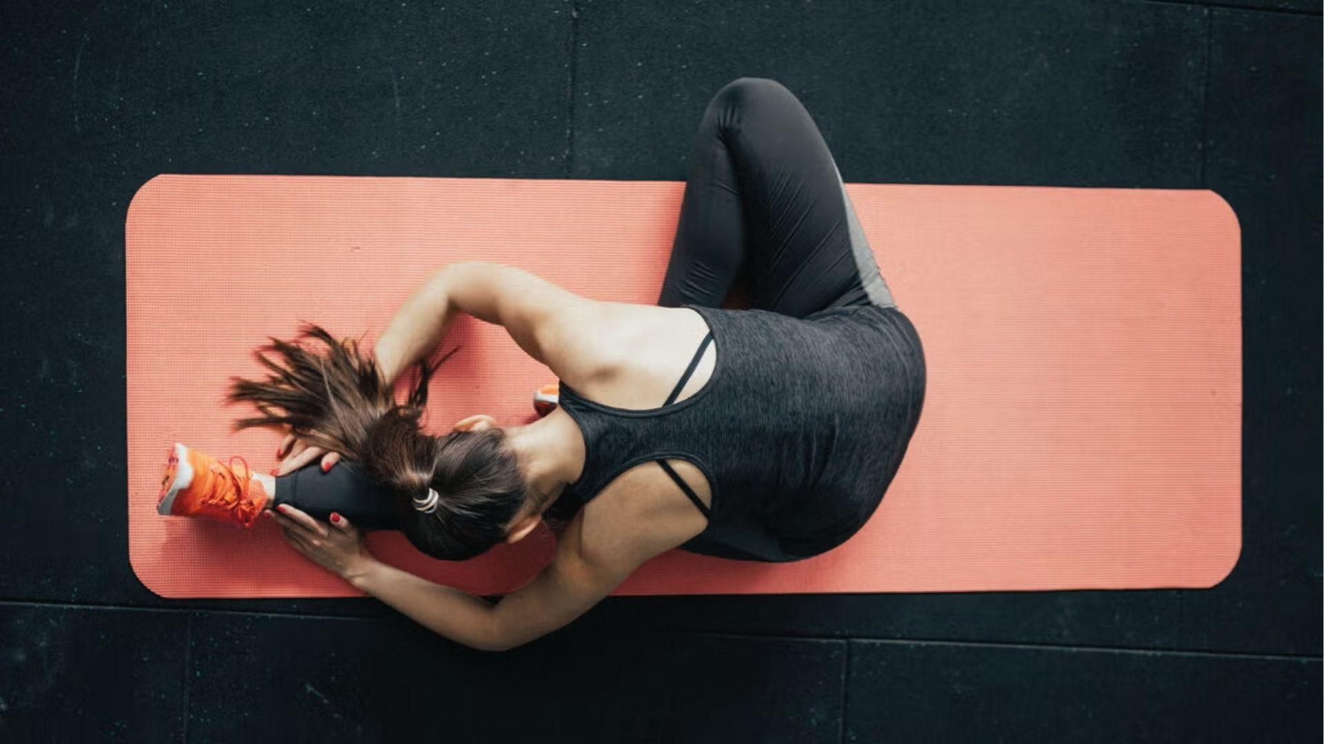 Overhead view of woman stretching on pink mat to improve mobility in 28 day calisthenics.