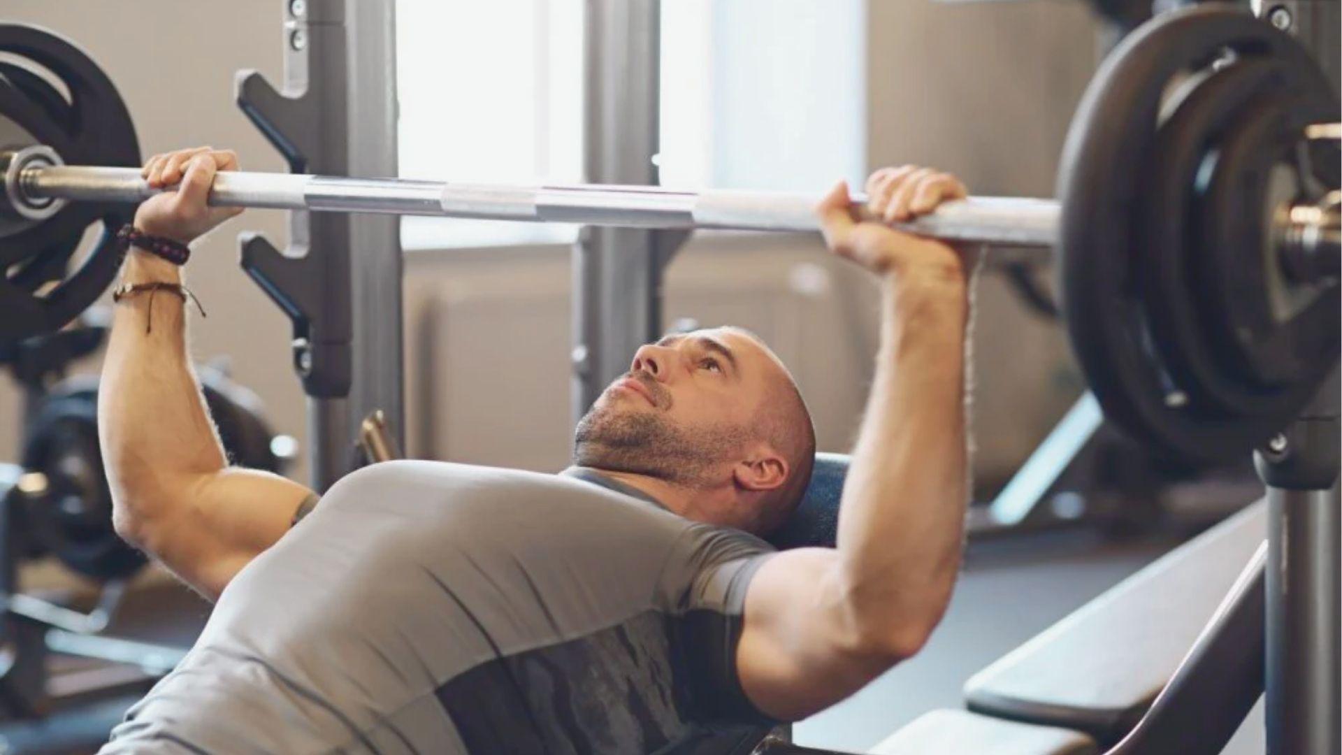 Close-up of a lifter performing bench press with a thumbless suicide grip.