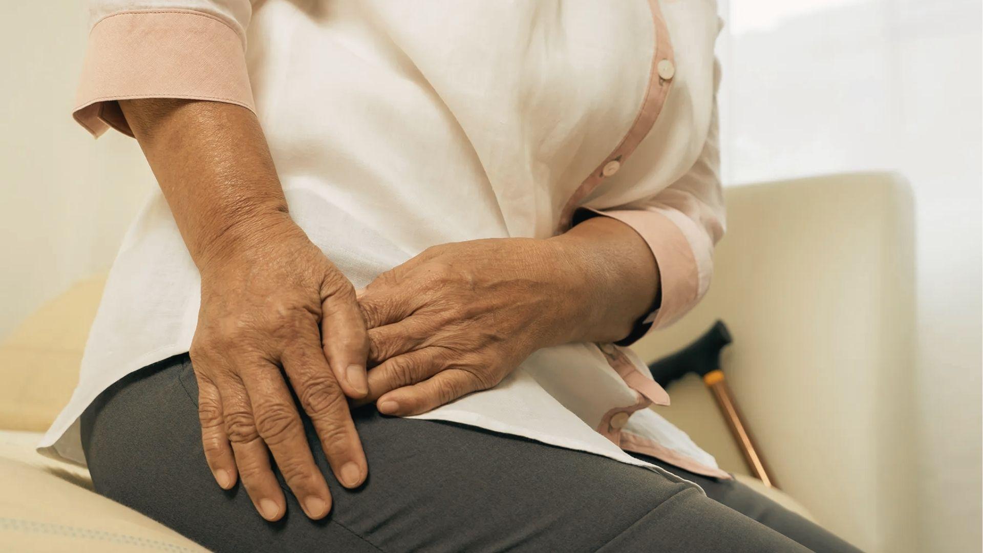 A woman in gray activewear does seated spinal twist to reduce hip stiffness after sitting.
