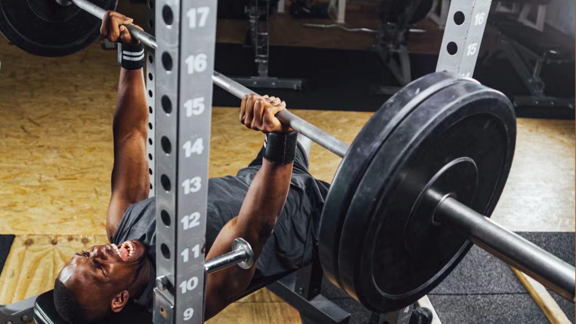 A person performing a bench press in the gym, showing how lifting strength standards can vary based on bodyweight.