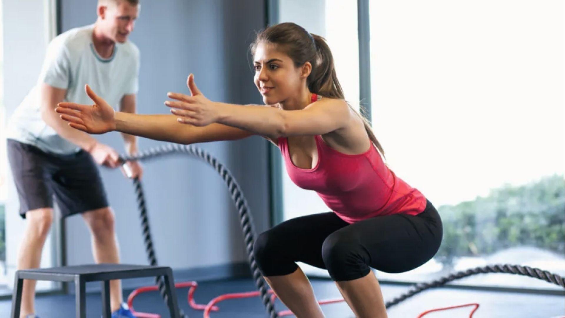 Woman in deep squat at gym engaging glutes, the largest muscles for strength and posture