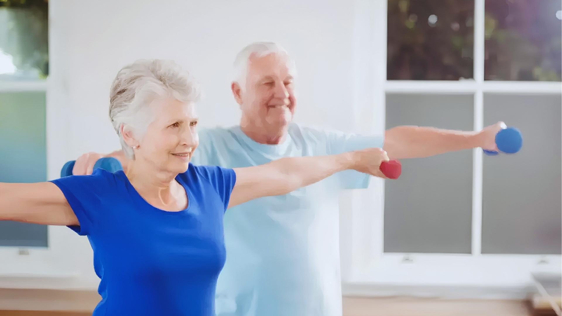 Senior man and woman in blue shirts lift light dumbbells laterally while smiling in the bright home gym.