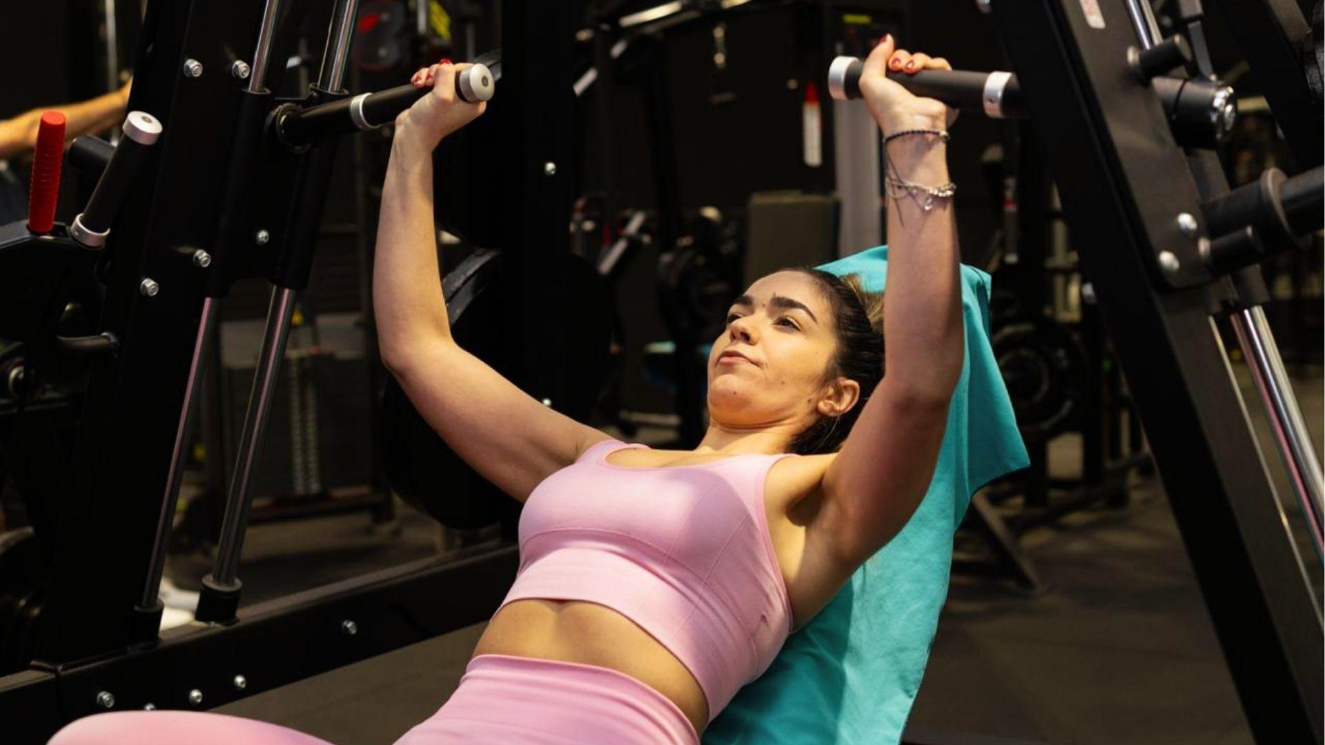 Person doing a chest exercise with dumbbells on a workout bench.